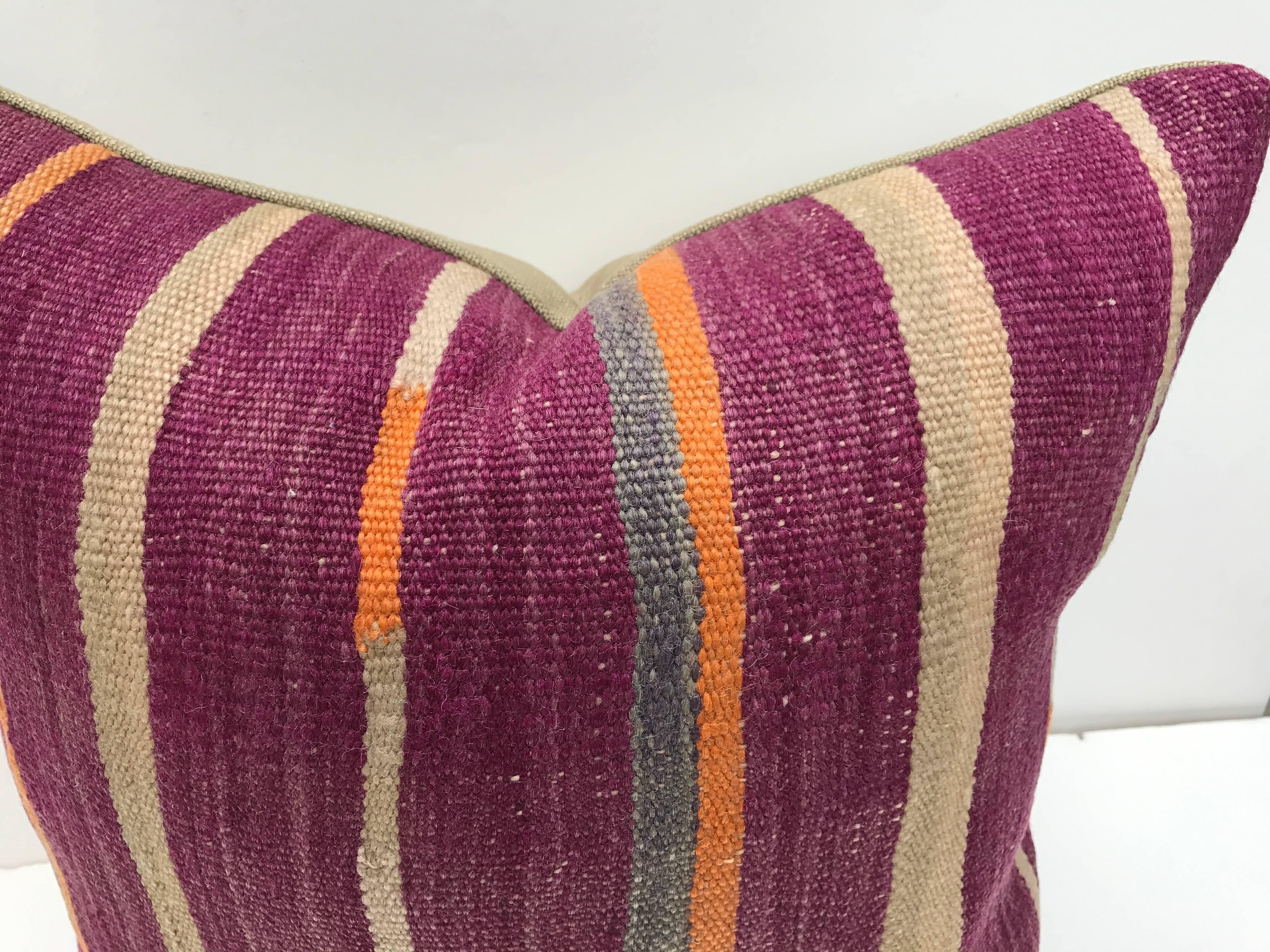Custom pillows cut from a vintage hand loomed wool Moroccan Berber rug from the Atlas Mountains. Flat-weave stripes have good color and wool is soft and lustrous. Pillow is backed in linen, filled with an insert of 50/50 down and feathers and
