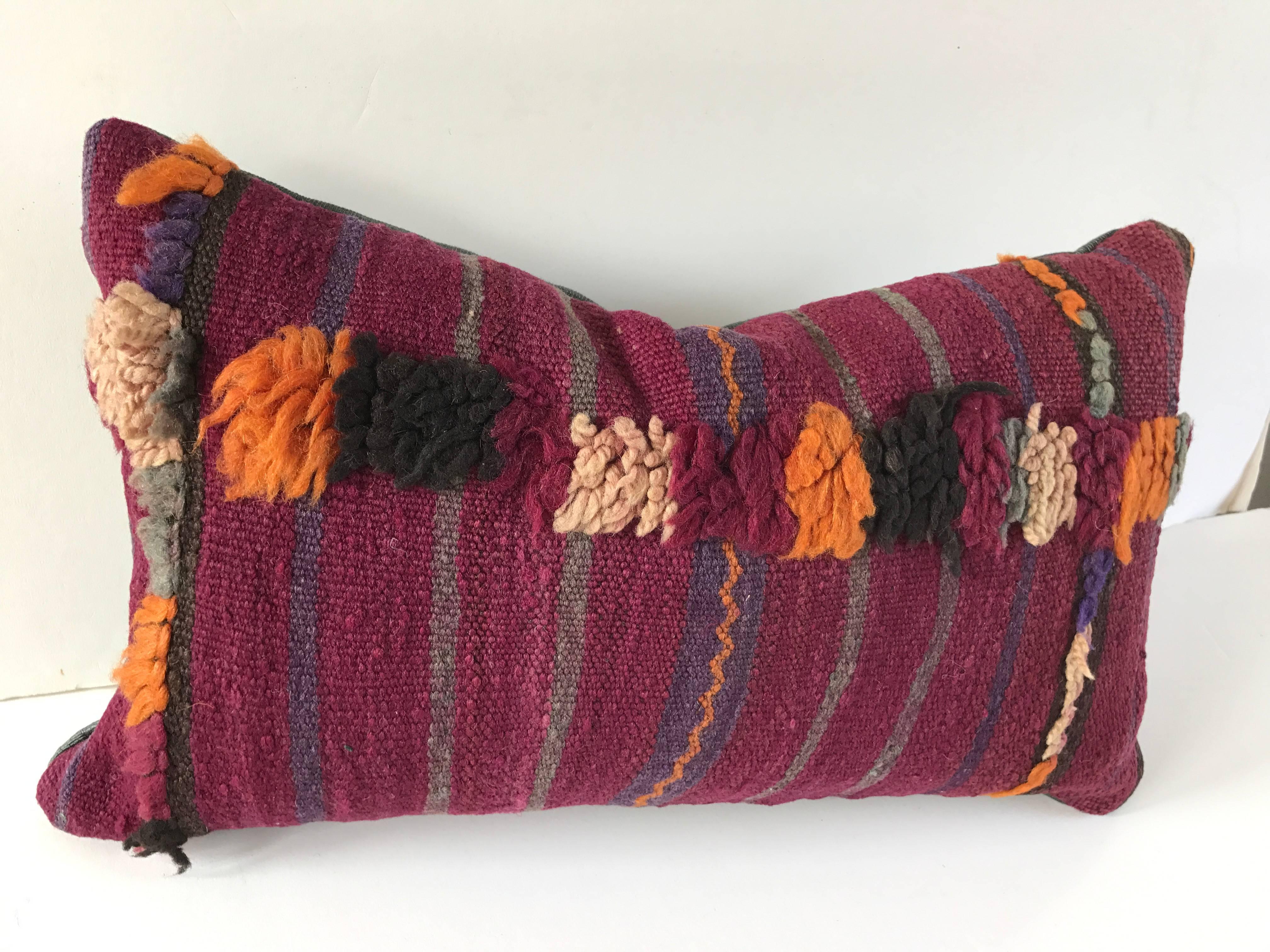 Custom pillow cut from a vintage hand loomed wool Moroccan Berber rug from the Atlas Mountains. Stripes are embellished with tufted wool designs. Pillow is backed in a teal silk/linen textile, filled with an insert of 50/50 down and feathers and