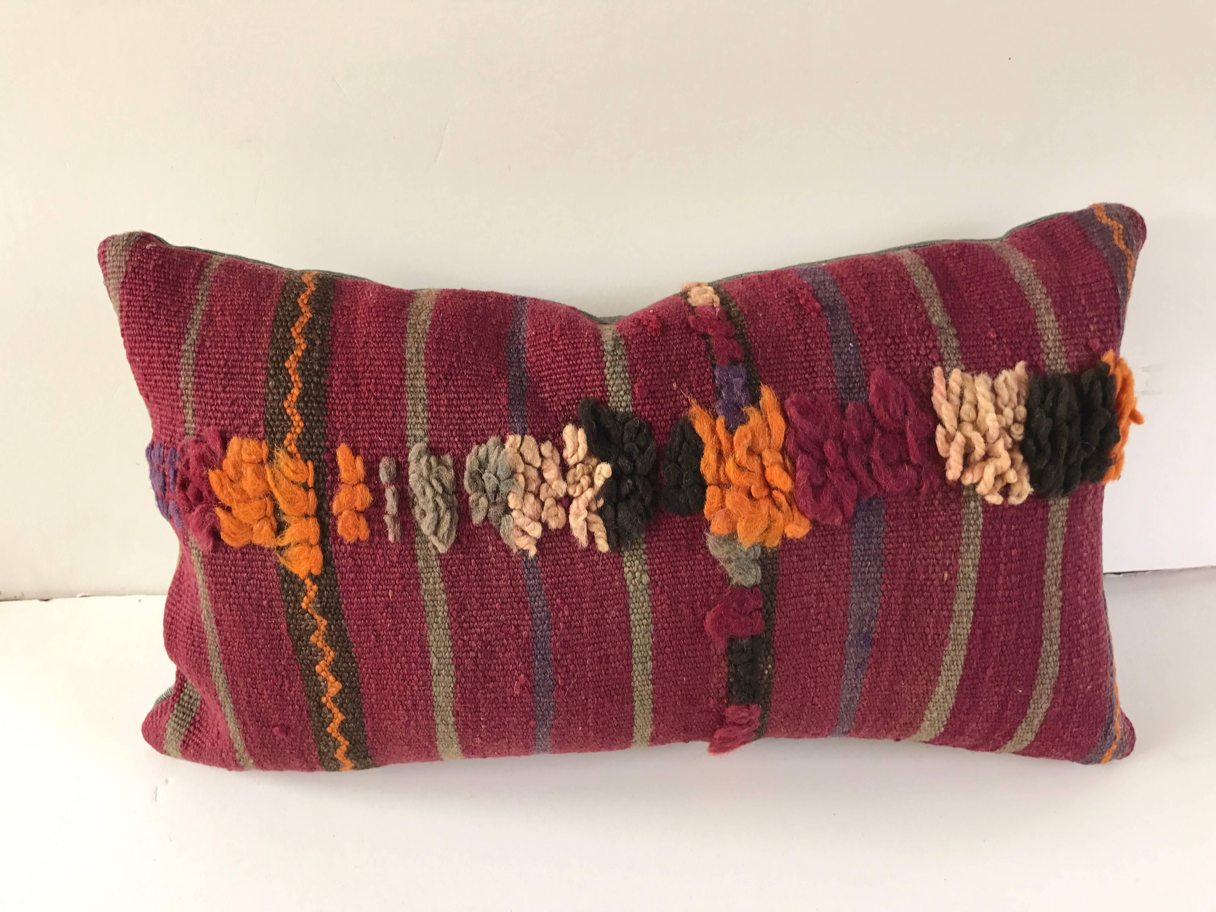 Custom pillow cut from a vintage hand-loomed wool Moroccan Berber rug from the Atlas Mountains. Stripes are embellished with tufted wool designs. Pillow is backed in a teal silk/.linen, filled with an insert of 50/50 down and feathers and hand-sewn