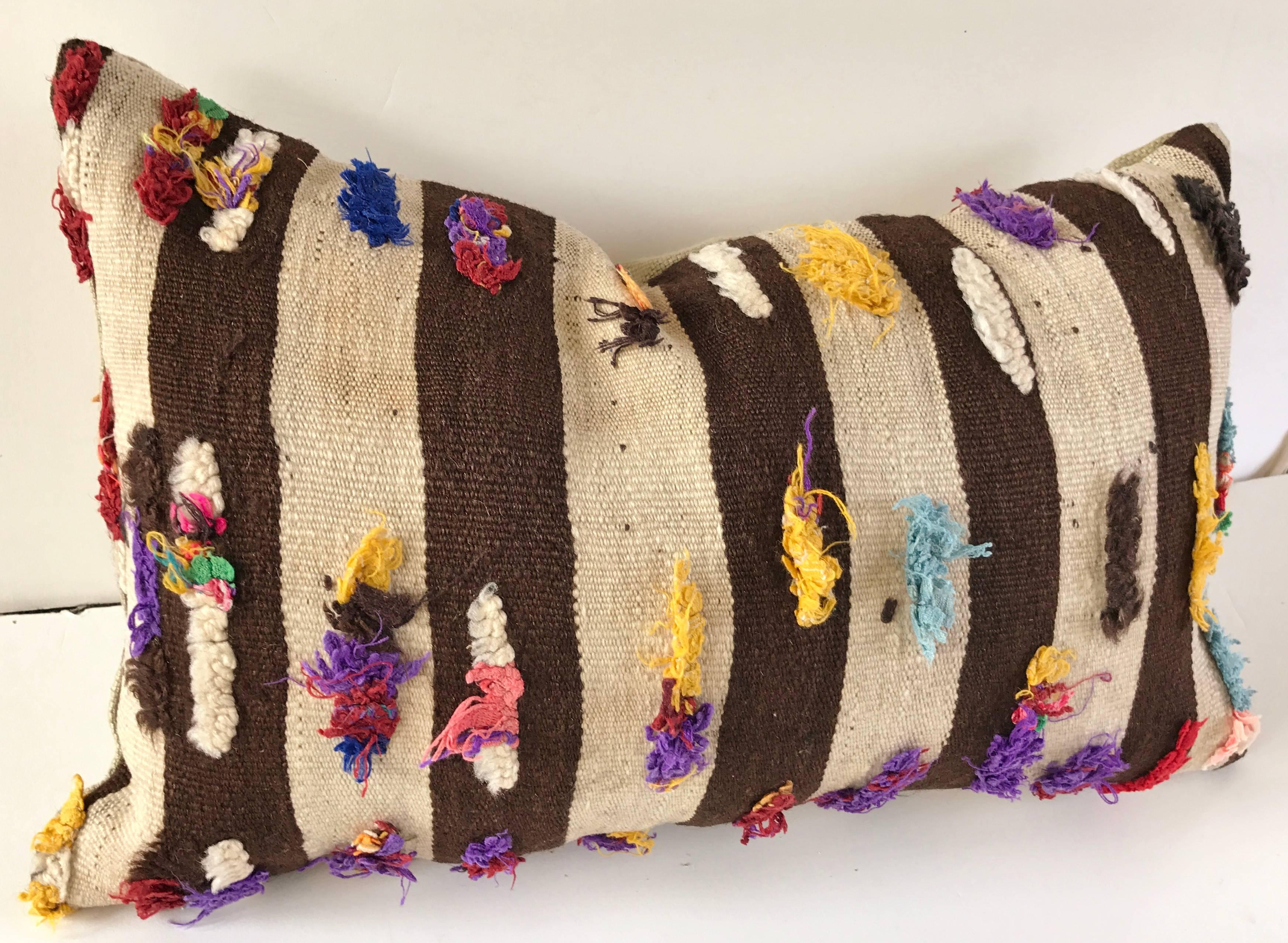 Custom pillow cut from a vintage hand loomed wool Moroccan Berber rug from the Atlas Mountains.  Flat weave stripes are embellished with colorful tufts.  Pillow is backed in linen, filled with an insert of 100% down and hand sewn closed.  All custom