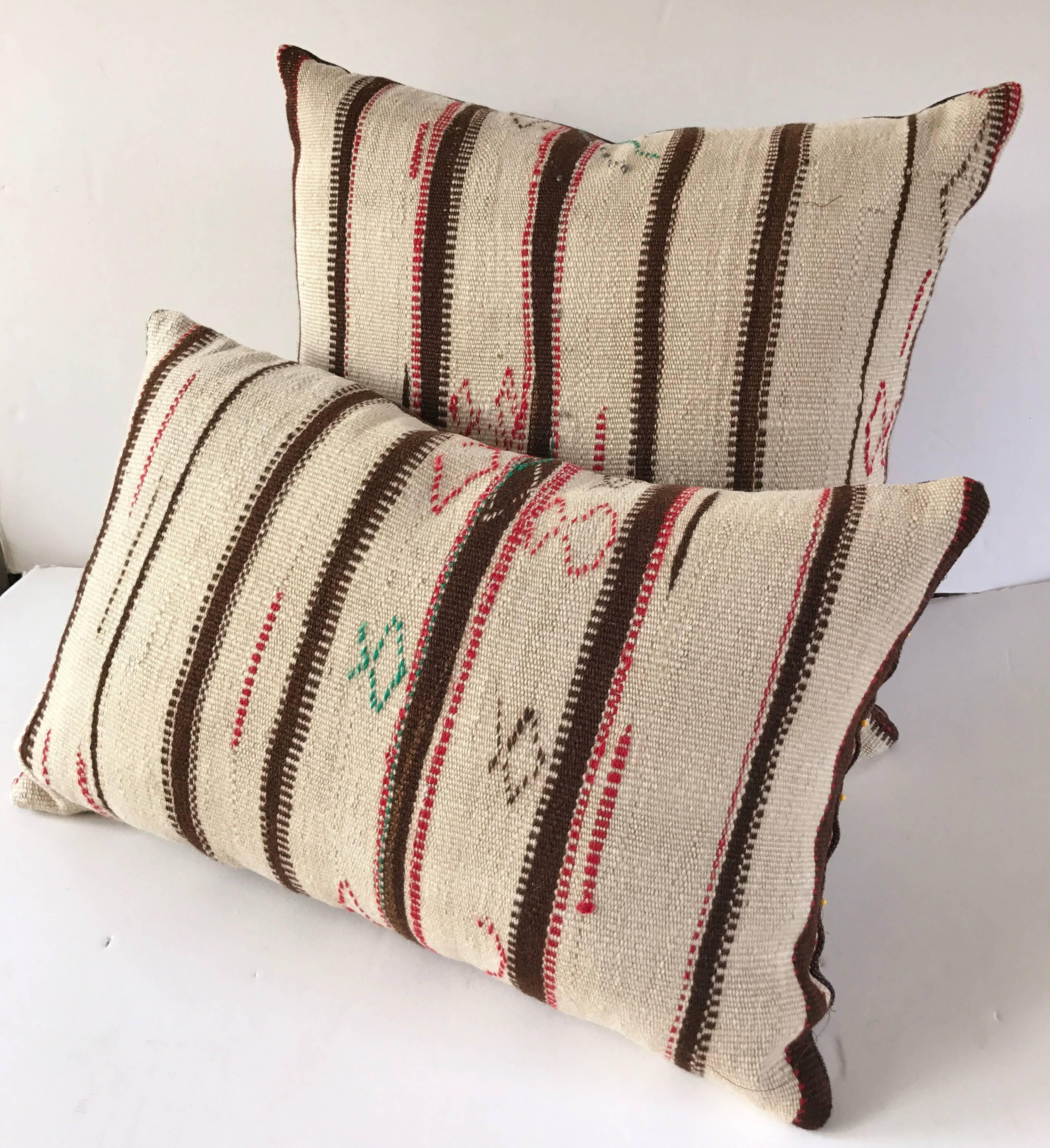 Custom pillow cut from a hand-loomed wool Moroccan Berber rug from the Atlas Mountains. Flat-weave stripes are embellished with tribal embroidered designs. Pillow is backed in a brown linen blend, filled with an insert of 100% down and hand-sewn