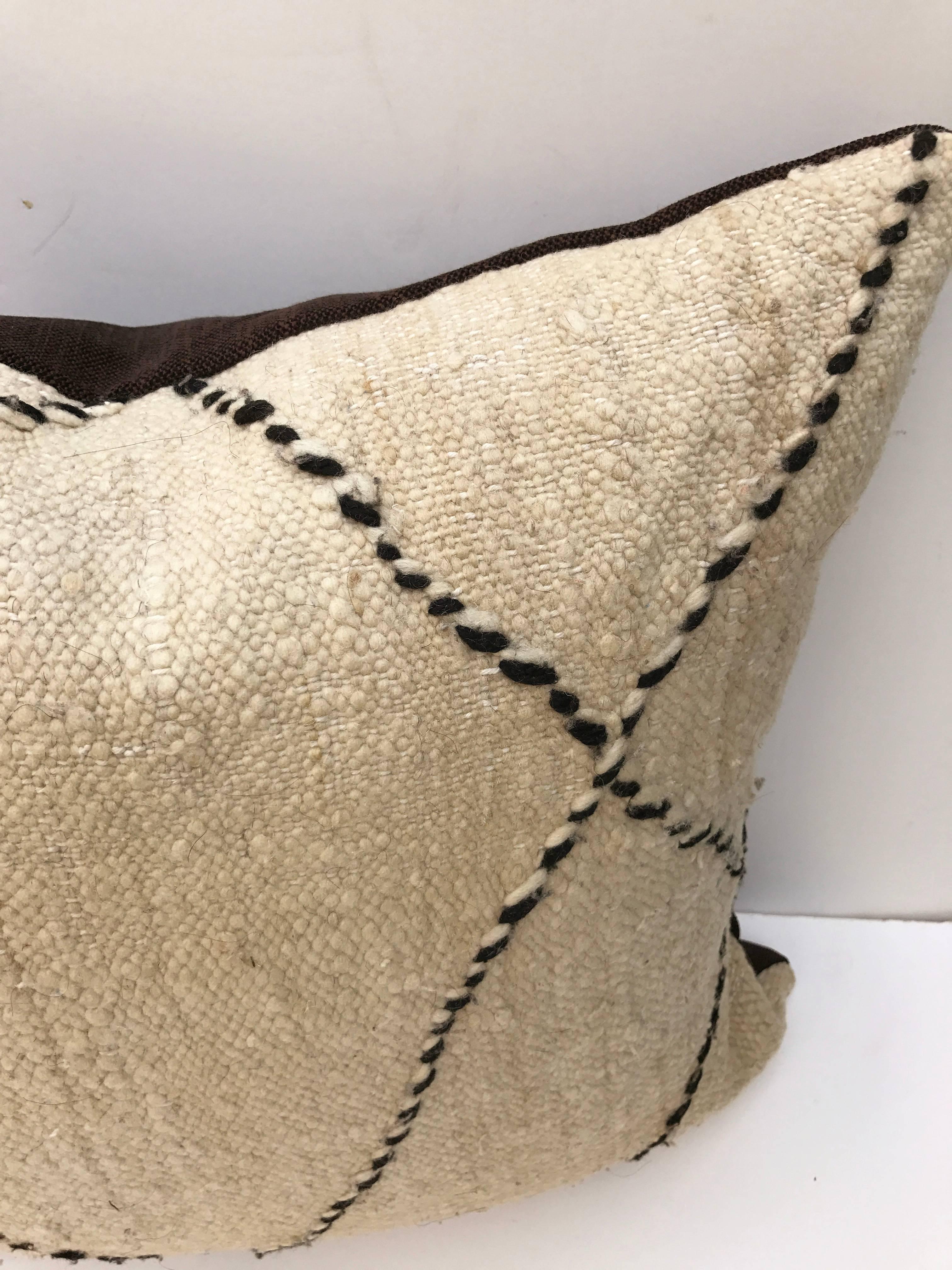 Custom pillow cut from a vintage hand loomed wool Moroccan Berber rug from the Atlas Mountains. Flat-weave with a woven tribal criss cross design from dark brown wool. Pillow is backed in a dark brown linen blend, filled with an insert of 50/50 down