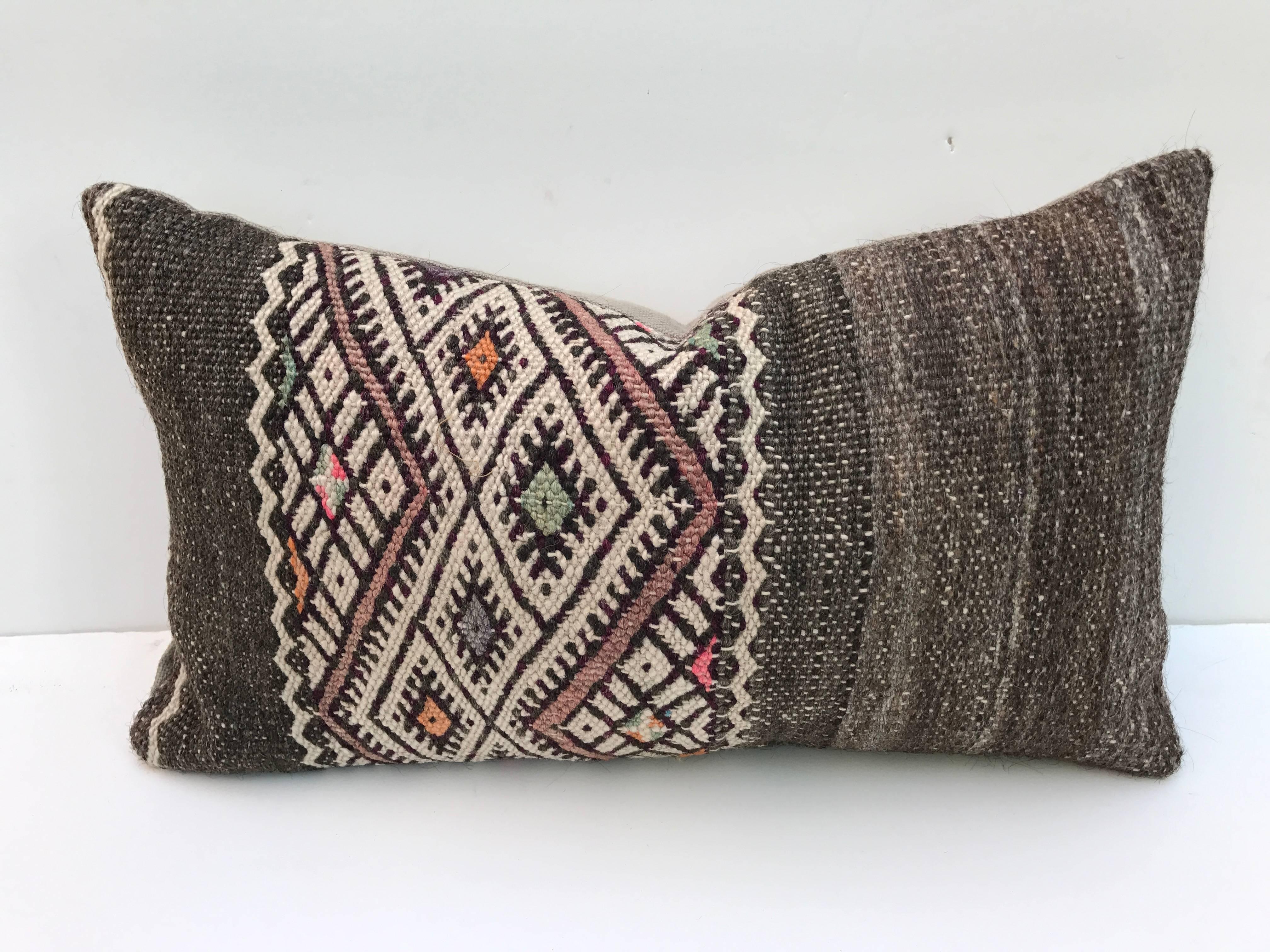 Pair of custom pillows cut from a hand-loomed wool Moroccan Berber rug from the Atlas Mountains. Wool is a mix of sheep and goat hair with all natural dyes and a woven tribal design. Pillows are backed in linen, filled with an insert of 50/50 down