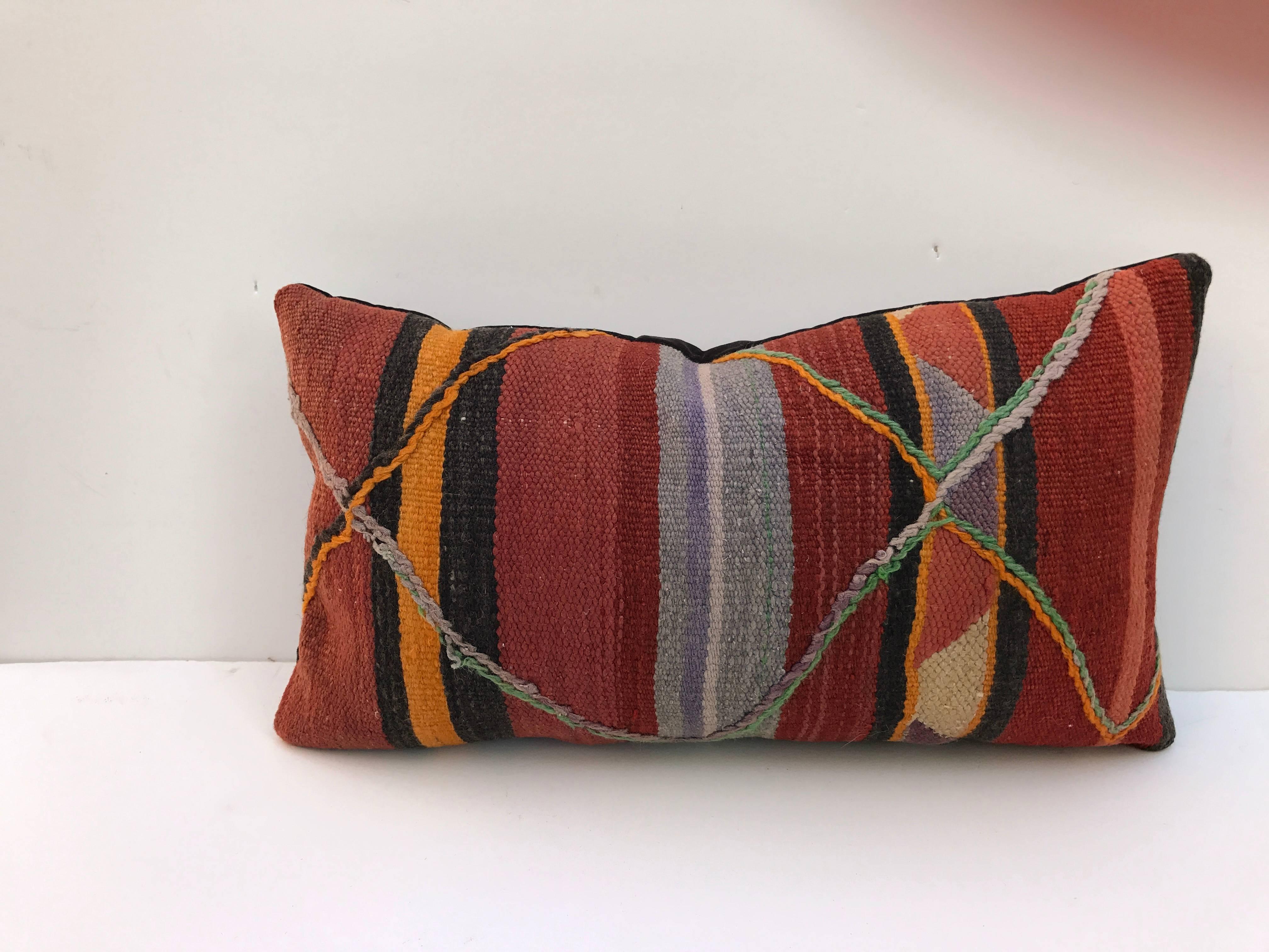 Custom pillow cut from a hand-loomed wool Moroccan Berber rug from the Atlas Mountains. Stripes are embellished with a raised wool tribal design. Wool is soft and lustrous with good color. Pillow is backed in a deep purple velvet, filled with an