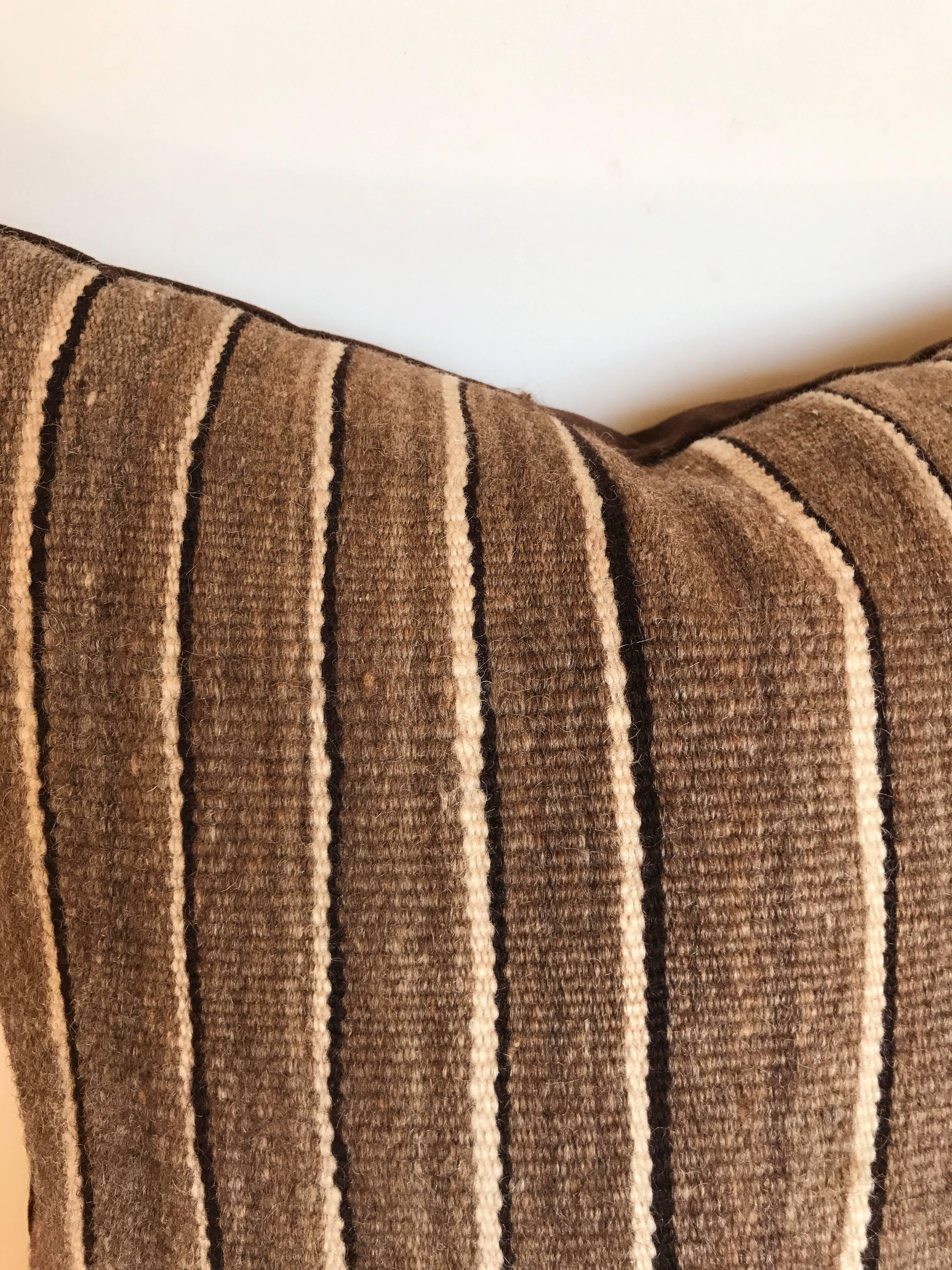 Custom pillow cut from a vintage hand-loomed wool Moroccan Berber rug from the Atlas Mountains. Wool is soft and lustrous with stripes in natural shades of brown, gray and cream. Pillow is backed in a dark brown velvet, filled with an insert of