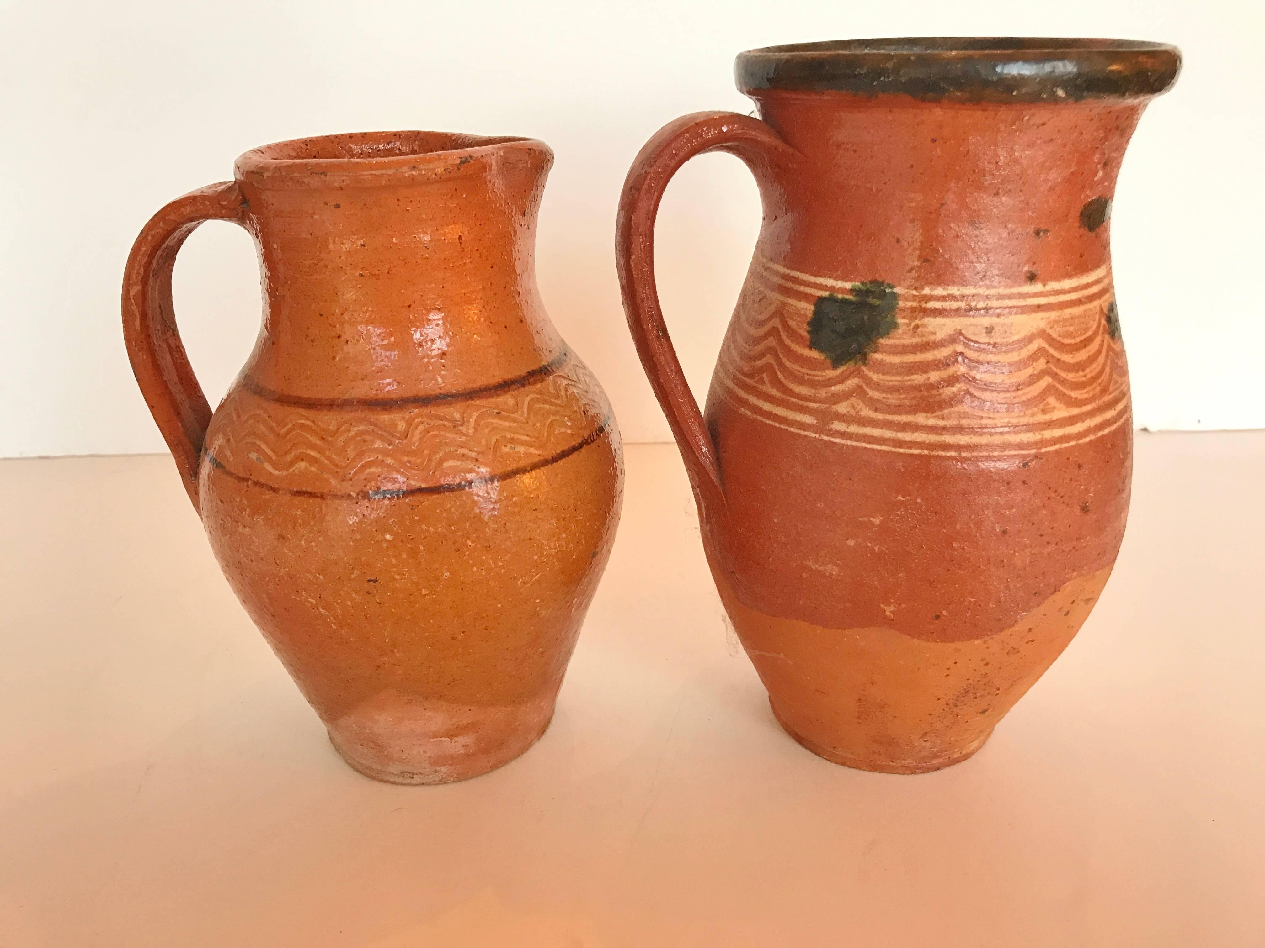 Transylvania vintage pottery pitchers. Hand-painted redware Folk Art from Romania. Decorative use. Measures: One pitcher is 8.25 inches high. Second pitcher is 7.5 inches high.