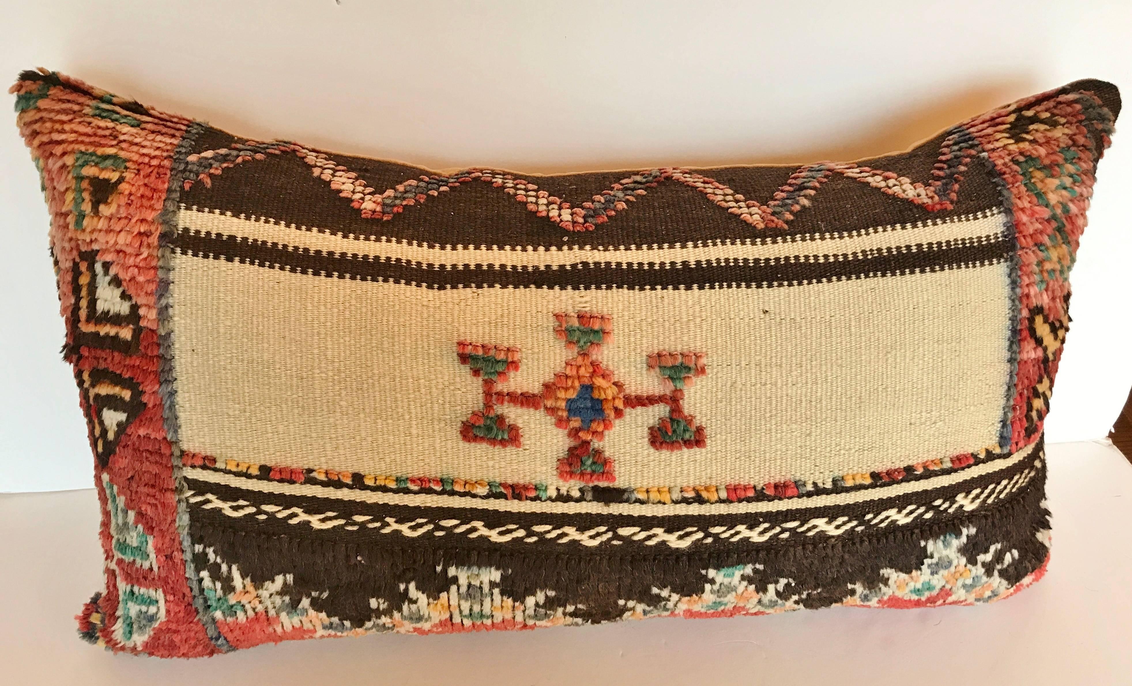 Custom pillow cut from a vintage hand loomed wool Moroccan rug made by the Berber tribes of the Atlas Mountains.  Wool is soft and lustrous with natural dyes.  The flat weave textile is embellished with woven tufted tribal designs.  Pillow is backed