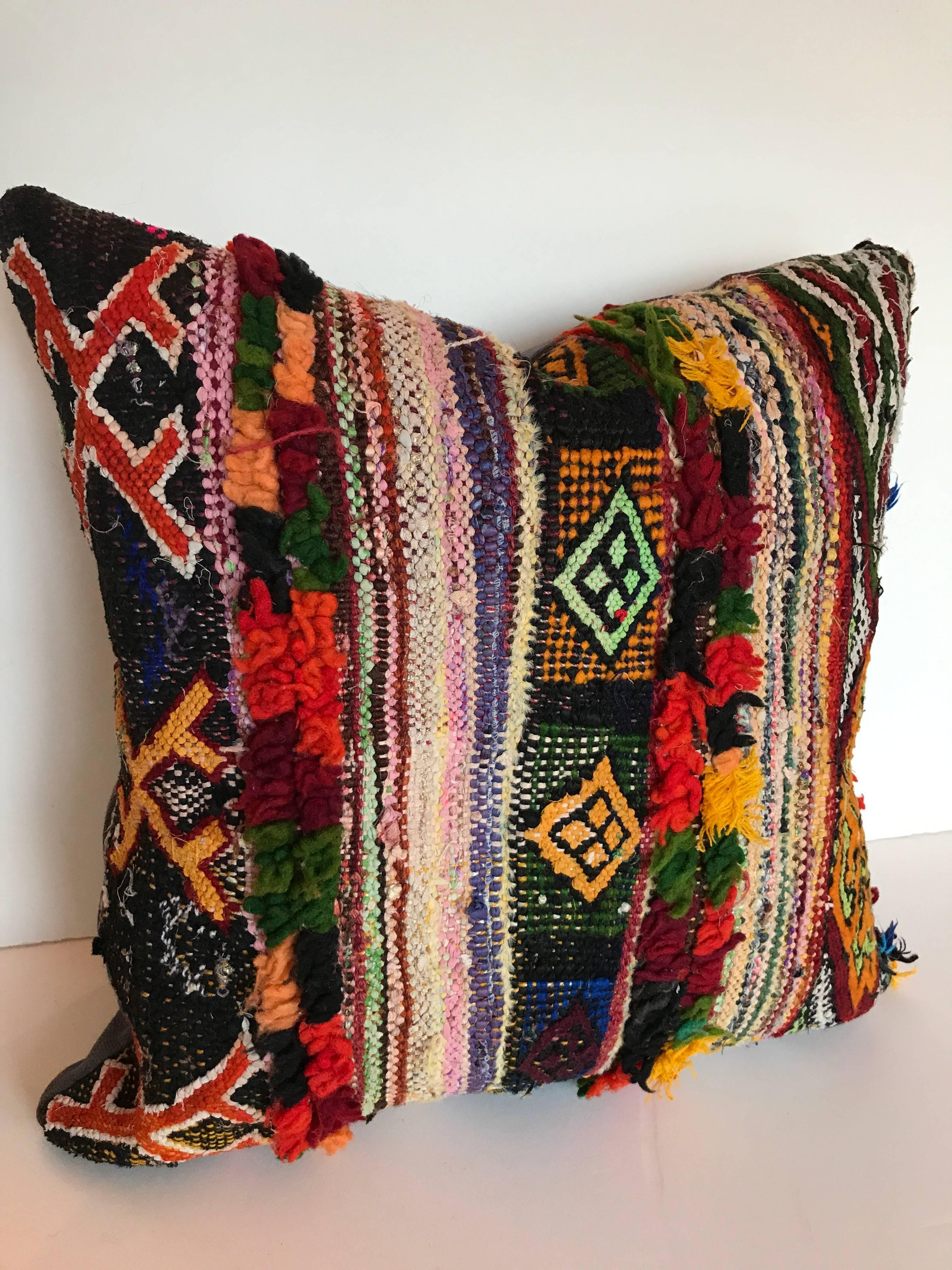 Custom pillow cut from a vintage hand loomed Boucherouite rug made by the Berber tribes of the Atlas Mountains.  The flat weave wool and cotton textiles is embellished with woven and tufted tribal designs.  The pillow is backed in linen, filled with