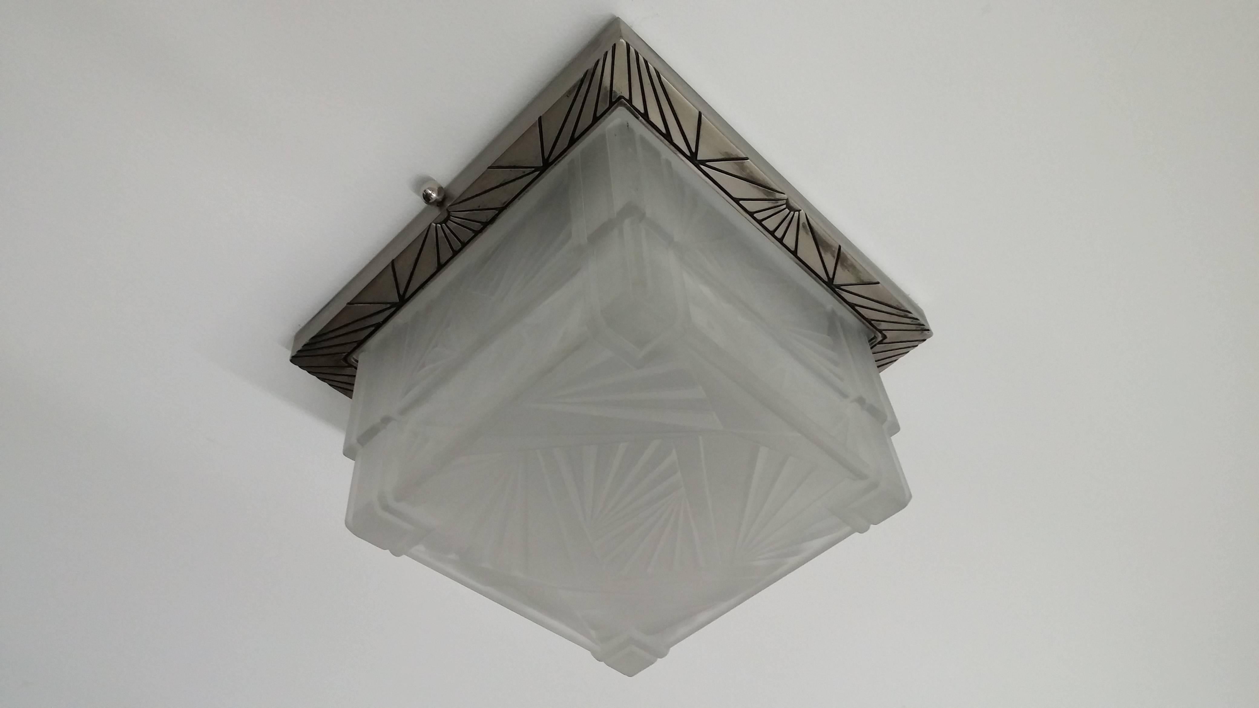 A French Art Deco square shaped flush mount or sconces. Shade is decorated with typical straight modern lines motif in clear frosted glass in great condition, mounted on a matching nickeled bronze decorative design frame. Fixture has modest wear