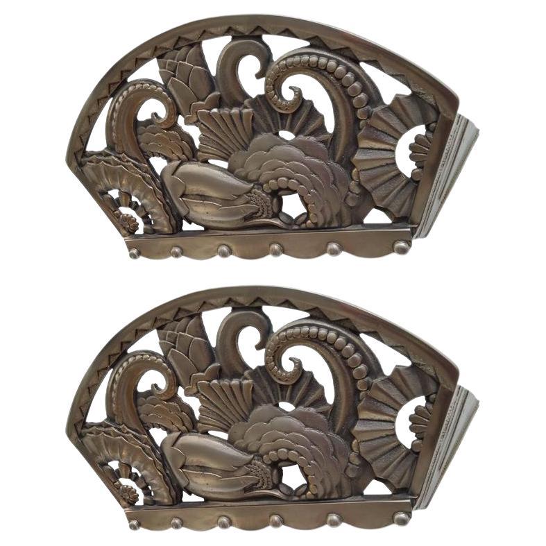 A pair of French Art Deco wall sconces with multi-dimensional intertwining flower façade motifs and decorative triangular sides in bronze in great condition. A flat frosted glass panel is encased within the mounting. Sconces have been re plated in