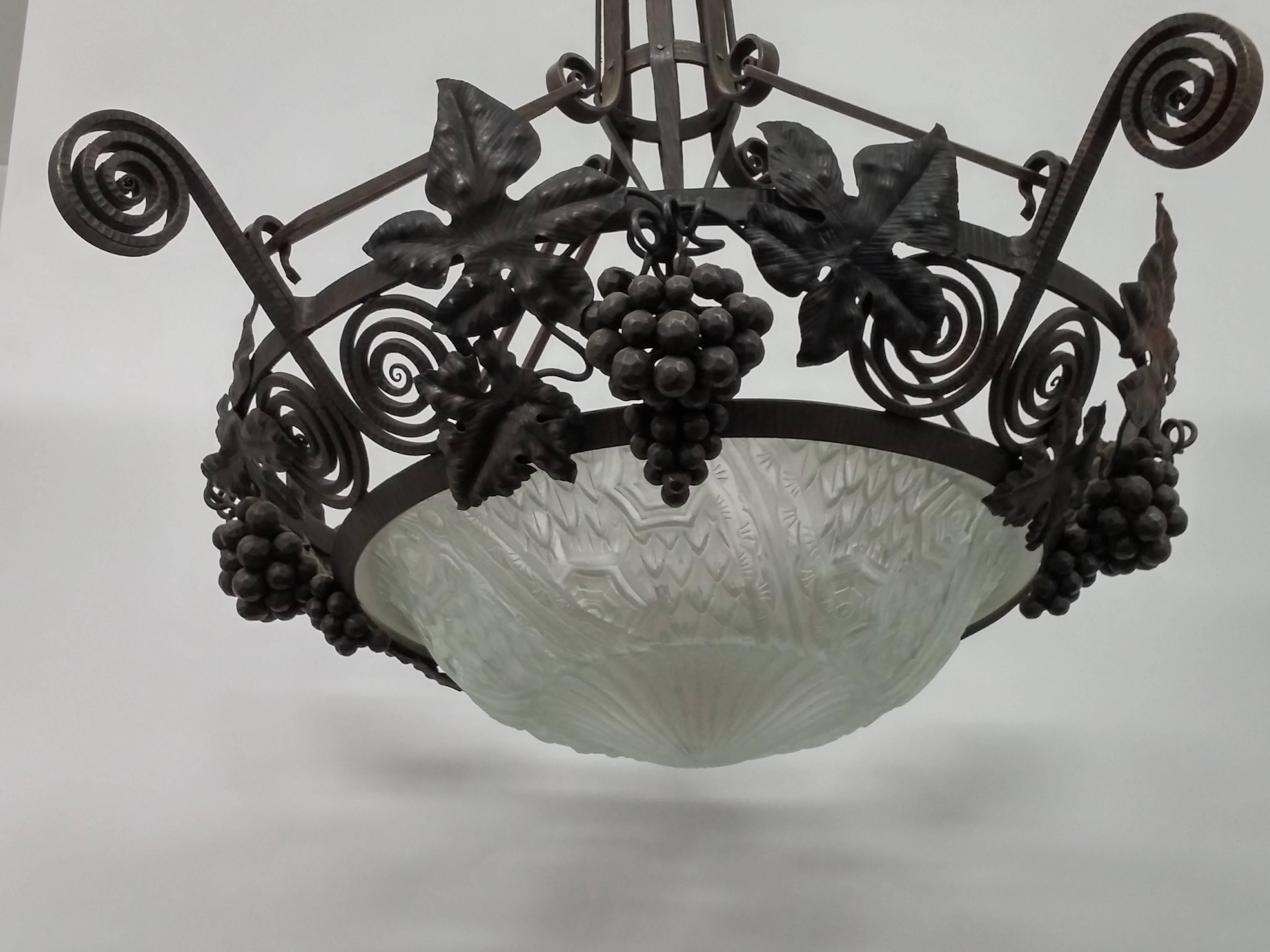 
A French Art Deco chandelier in wrought iron with grape details motiff enbracing a clear center glass shade by Schneider. Complimentary delivery WORLDWIDE. We are the rare source that specializes exclusively in French Art Deco for over two decades,