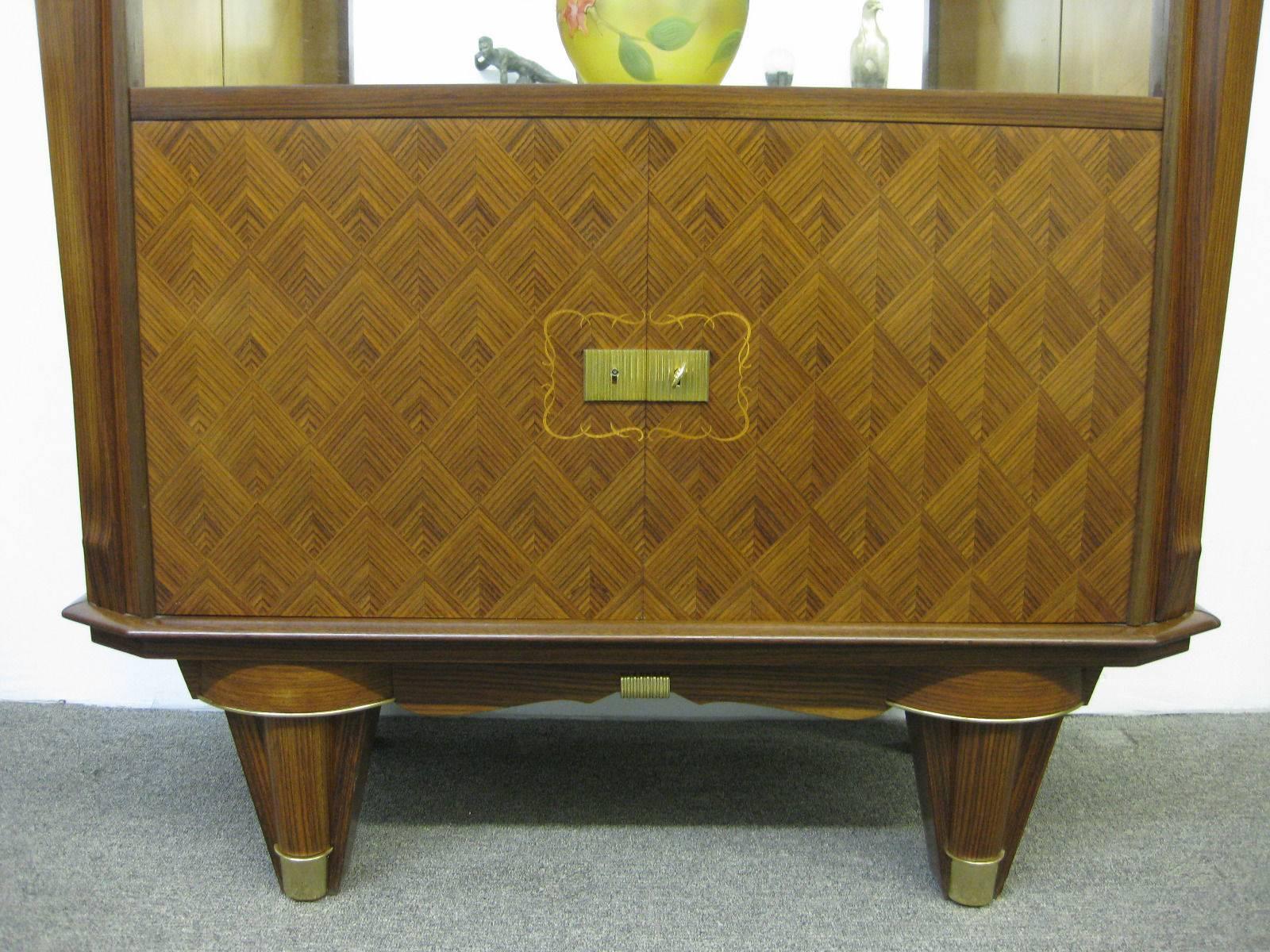 French Art Deco elegant rosewood showcase, display cabinet from the 1940's, attributed to Jules Leleu in a very good condition. Features intricate inlay marquetry details on both doors. Hardwere was replated in 24-karat gold. The Cabinet door has a