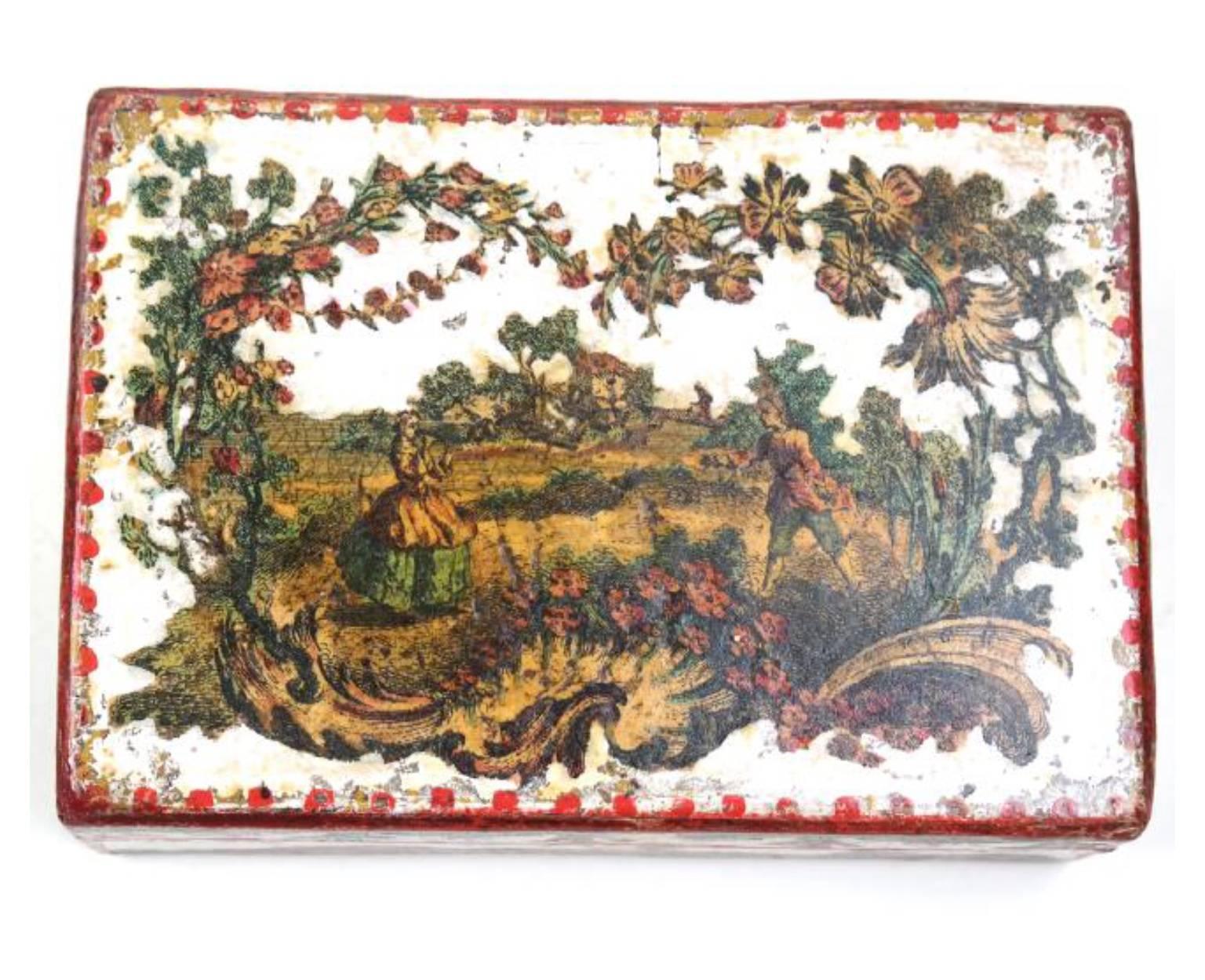 The papier mâché box depicting a landscape scene on a white ground with red trim on all sides.