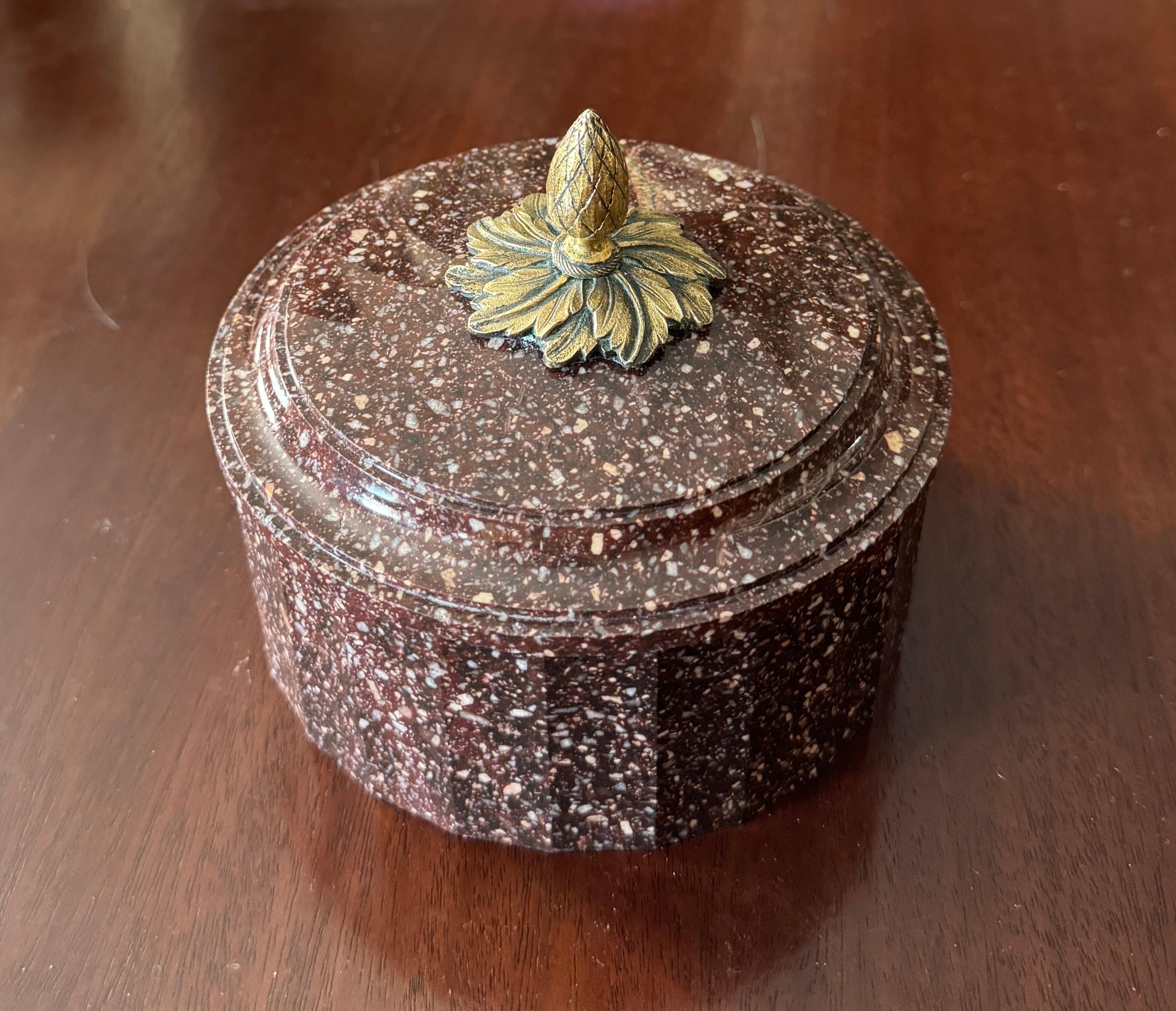 The delicately chamfered edges of the round tub and cover carved from Blyberg Porphyry with ormolu mounted acorn finial.