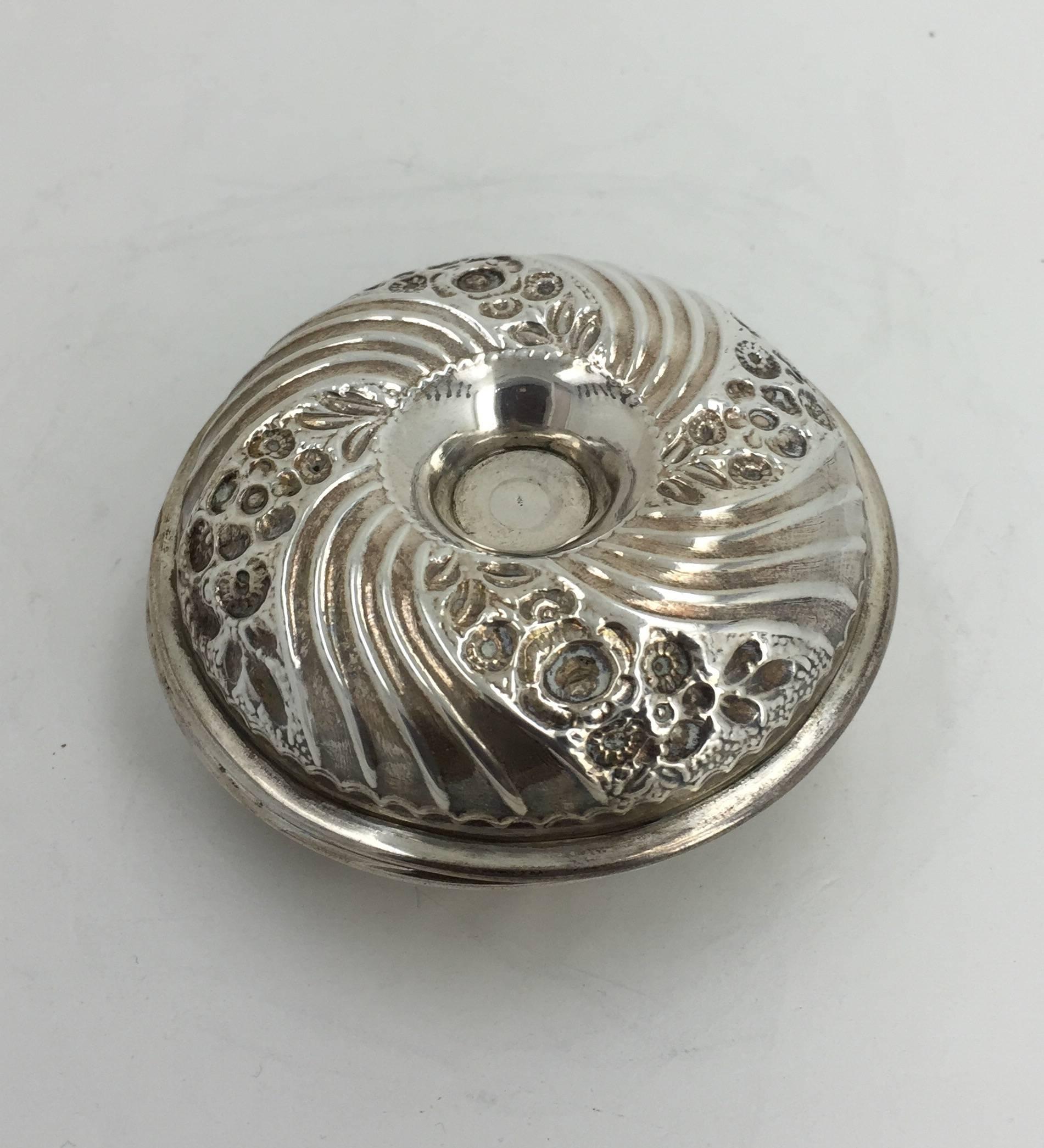 The closed flat round silver unscrews to reveal two repoussé candlestick holders and screw on bobeche.