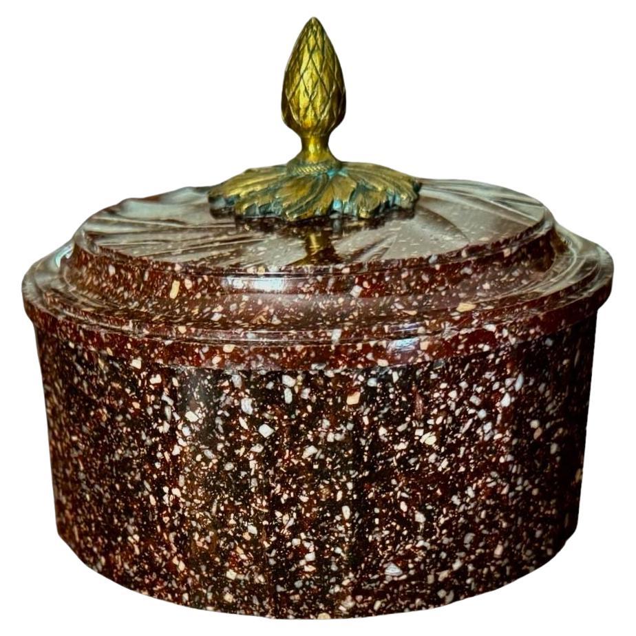 The delicately chamfered edges of the round tub and cover carved from Blyberg Porphyry with ormolu mounted acorn finial.