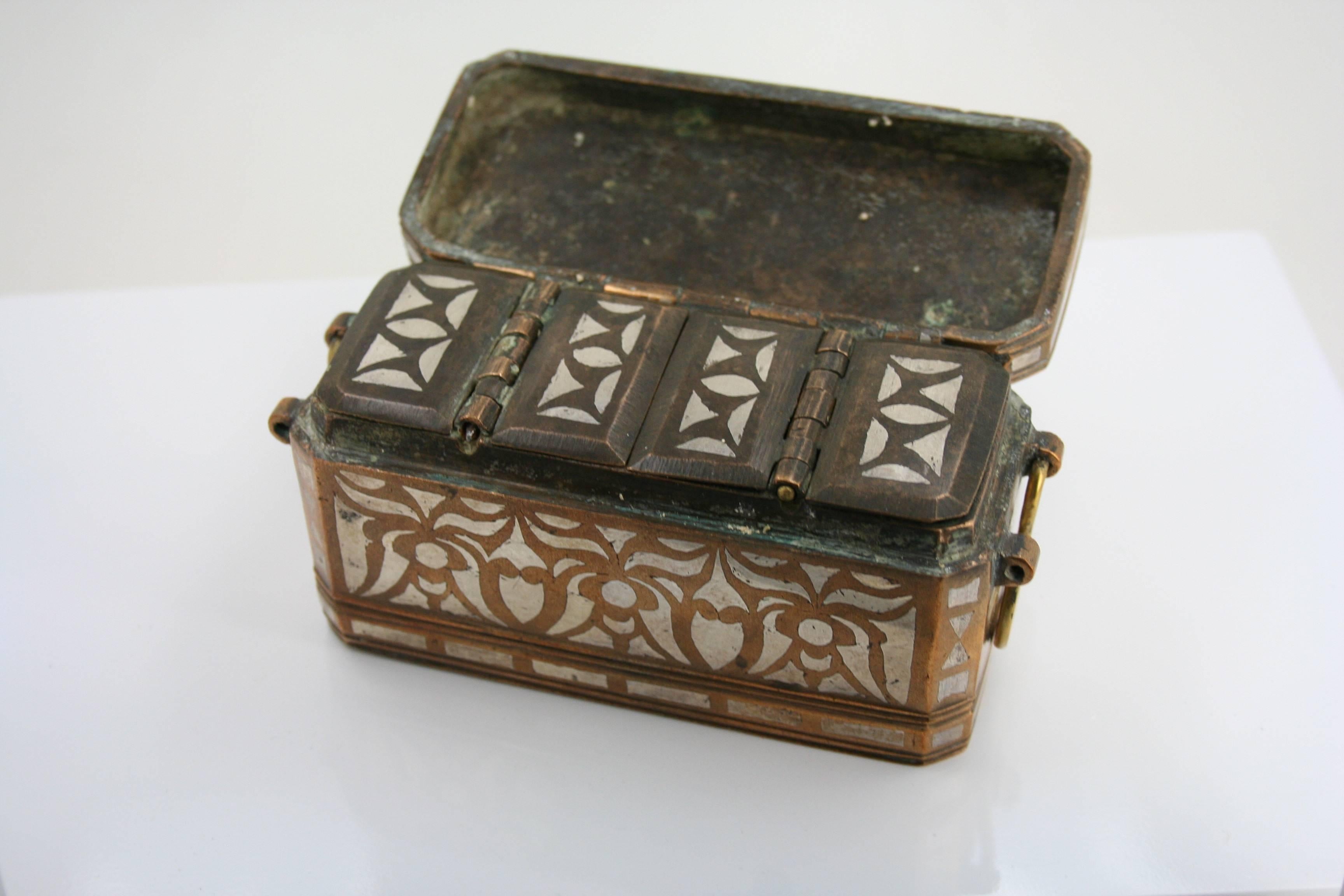The rectangular box with chamfered corners opening to reveal four panels/ three compartments with spatula on a chain.