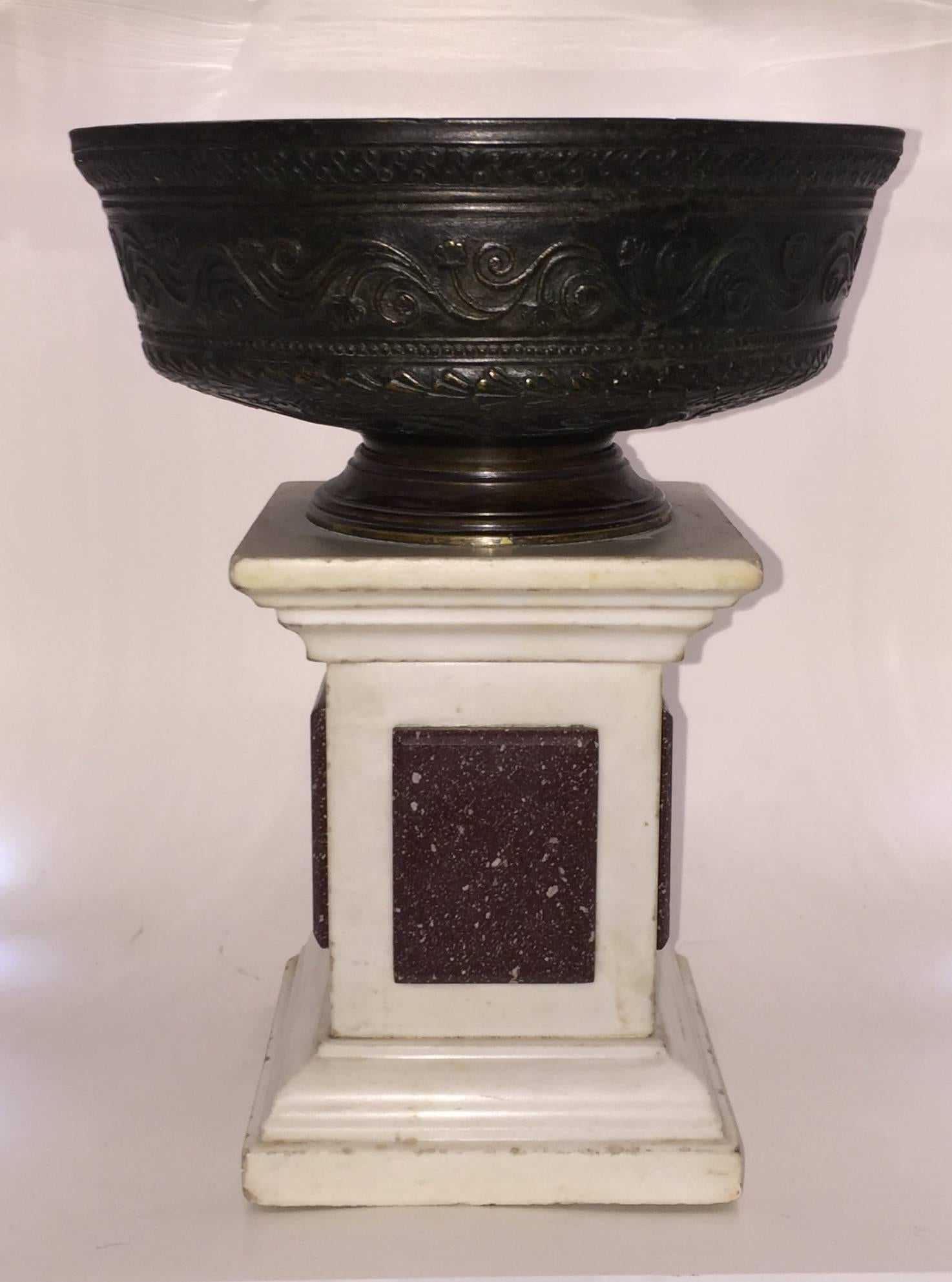 The bowl highly decorated, atop a white marble and porphyry base.