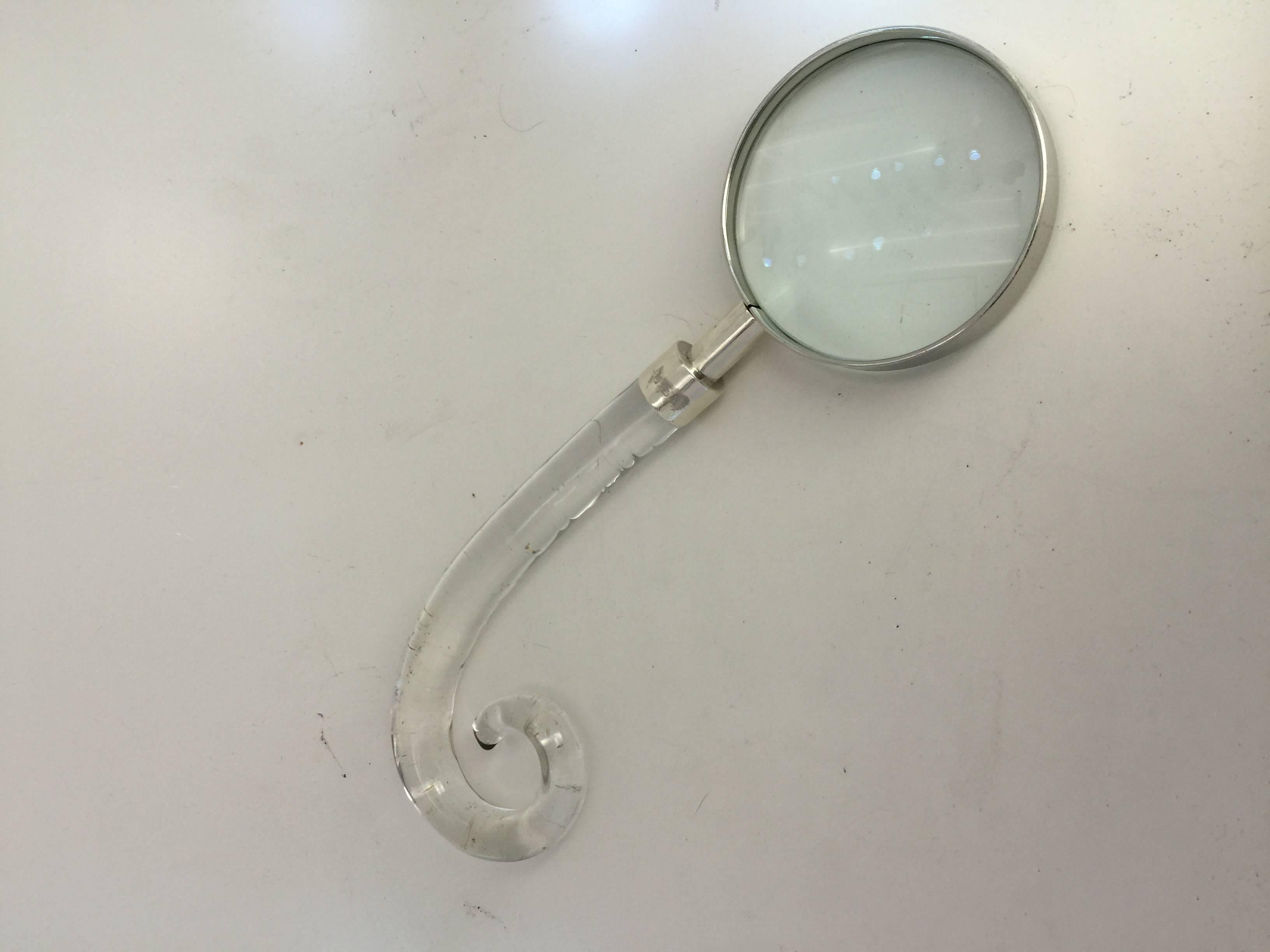 The curling glass handle with silver mount connecting to magnifying glass.