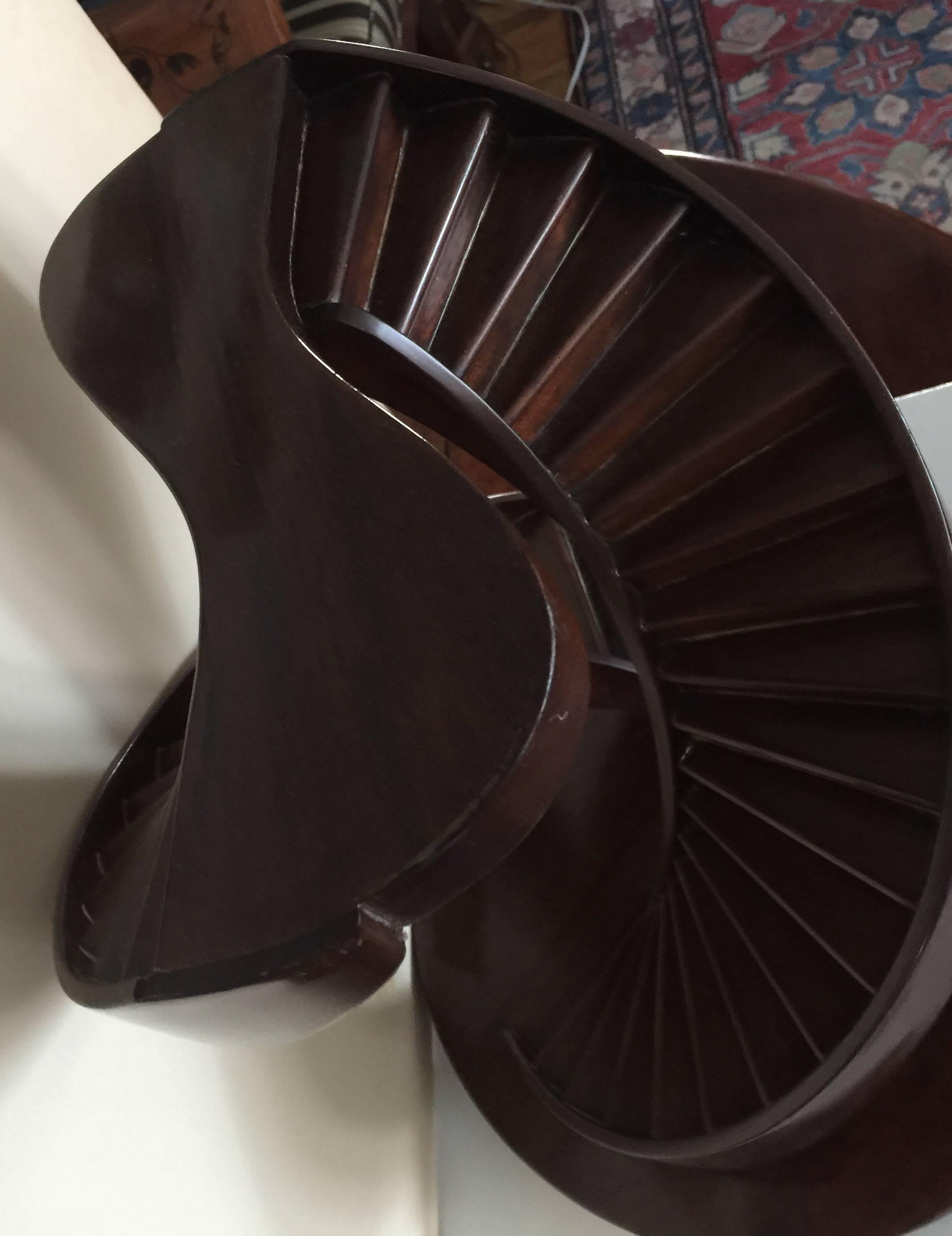 The double helix staircase mounted to a round mahogany base on three bun feet.