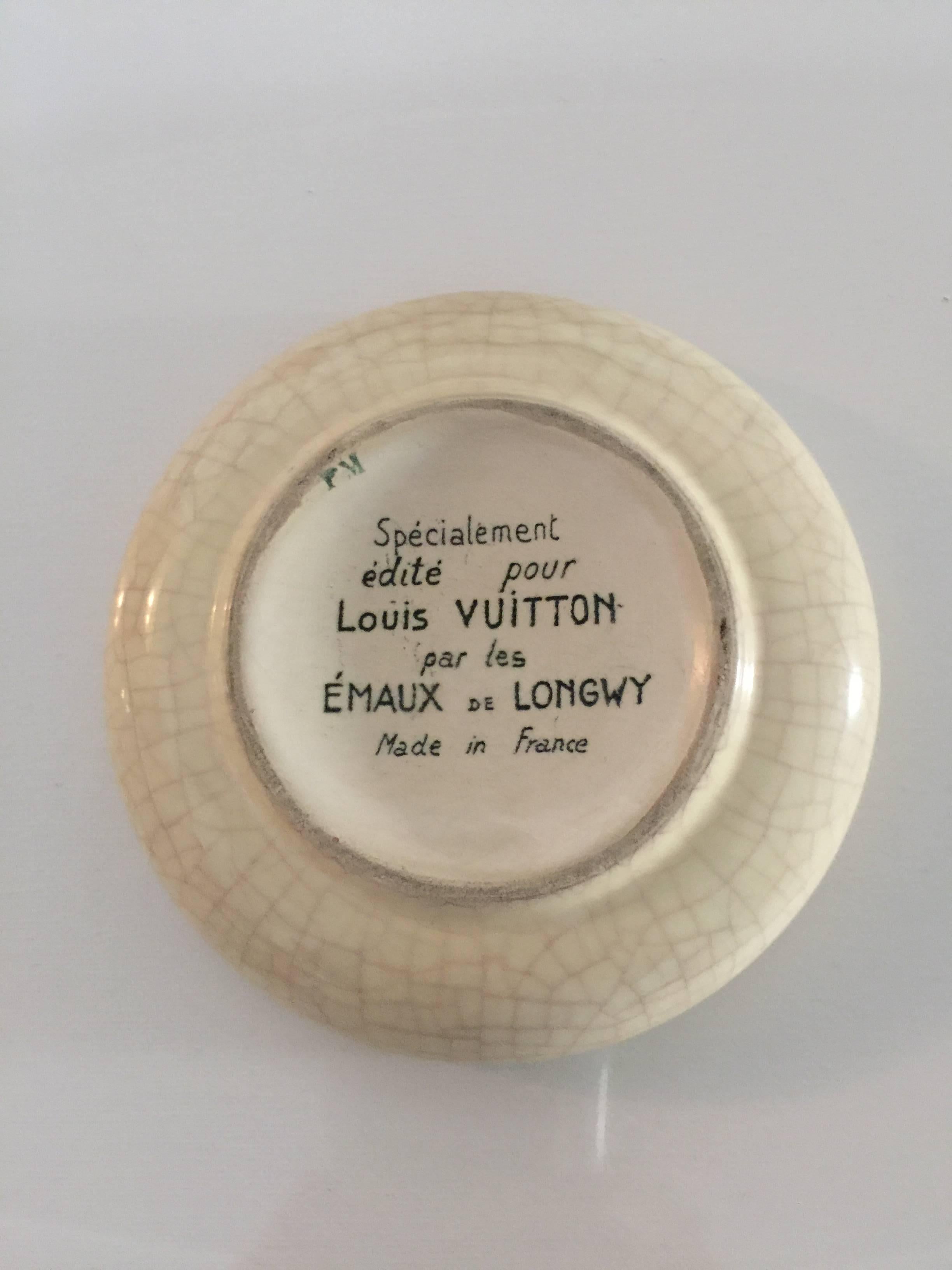 The enamel decorated bowl in the iconic Louis Vuitton logo.
Signed on reverse 'Specialment edite pour Louis Vuitton par les Emaux de Longwy, Made in France. Minute chip on rim.