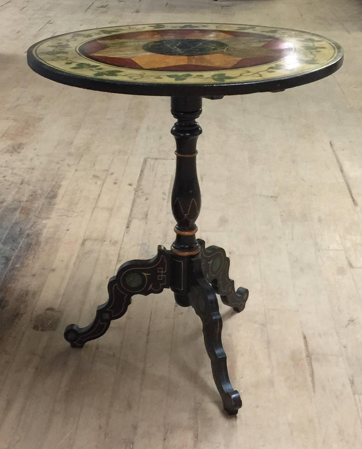 The tilt-top painted with faux marble design in the center surrounded by a vine and leaf pattern.