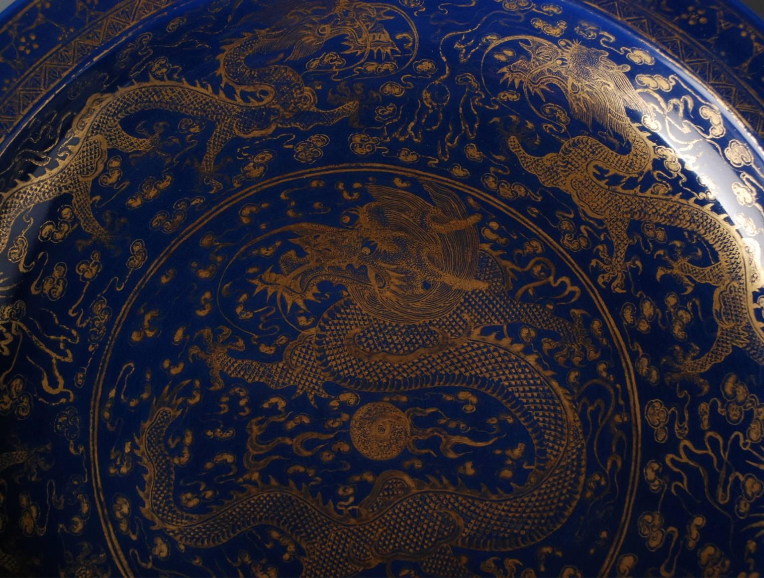 This Chinese porcelain charger is decorated in monochrome blue enamel, under glaze. The dragons’ decoration in gold is applied over the glaze. In China, the dragon is the symbol of the emperor, here depicted in the center and on the edge. These