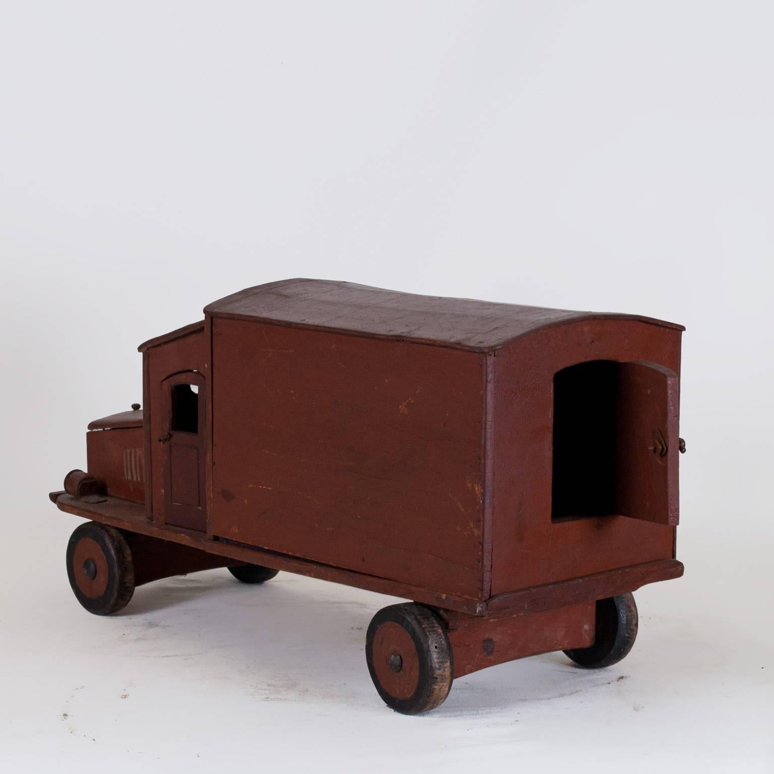 A dark red model truck of an antique French lorry with opening doors and removable back part, in good condition. Hand crafted in wood and hand painted. Minor fading, due to age. Wear consistent with age and use, circa 1920-1930, France.