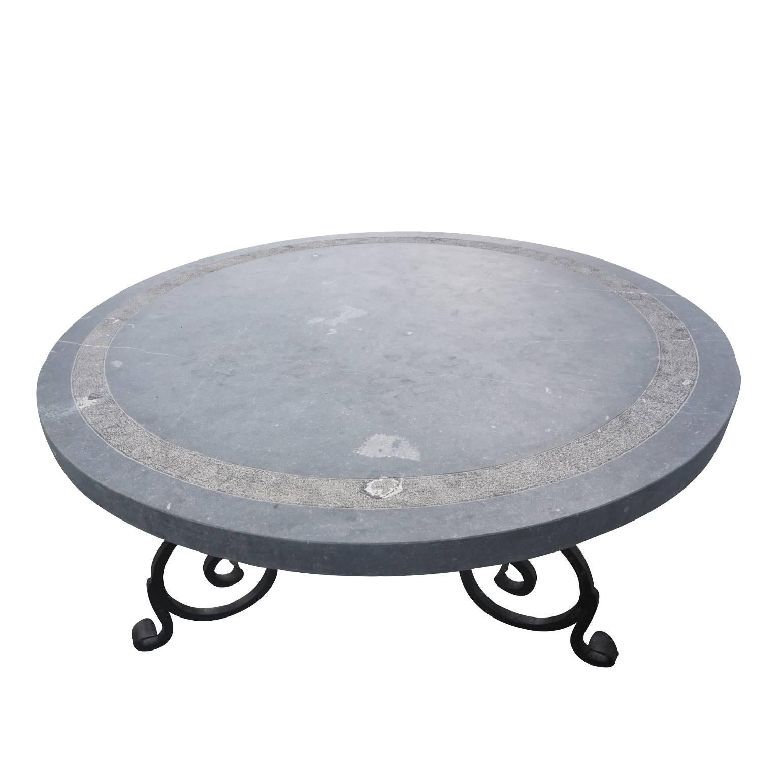 Large and impressive round Belgian blue stone top table with decorative chiselled rim on a honed surface. The heavy and impressive 19th Century base is made of hand-forged wrought iron with scroll deco in the 18th Century manner. 

Belgian bluestone