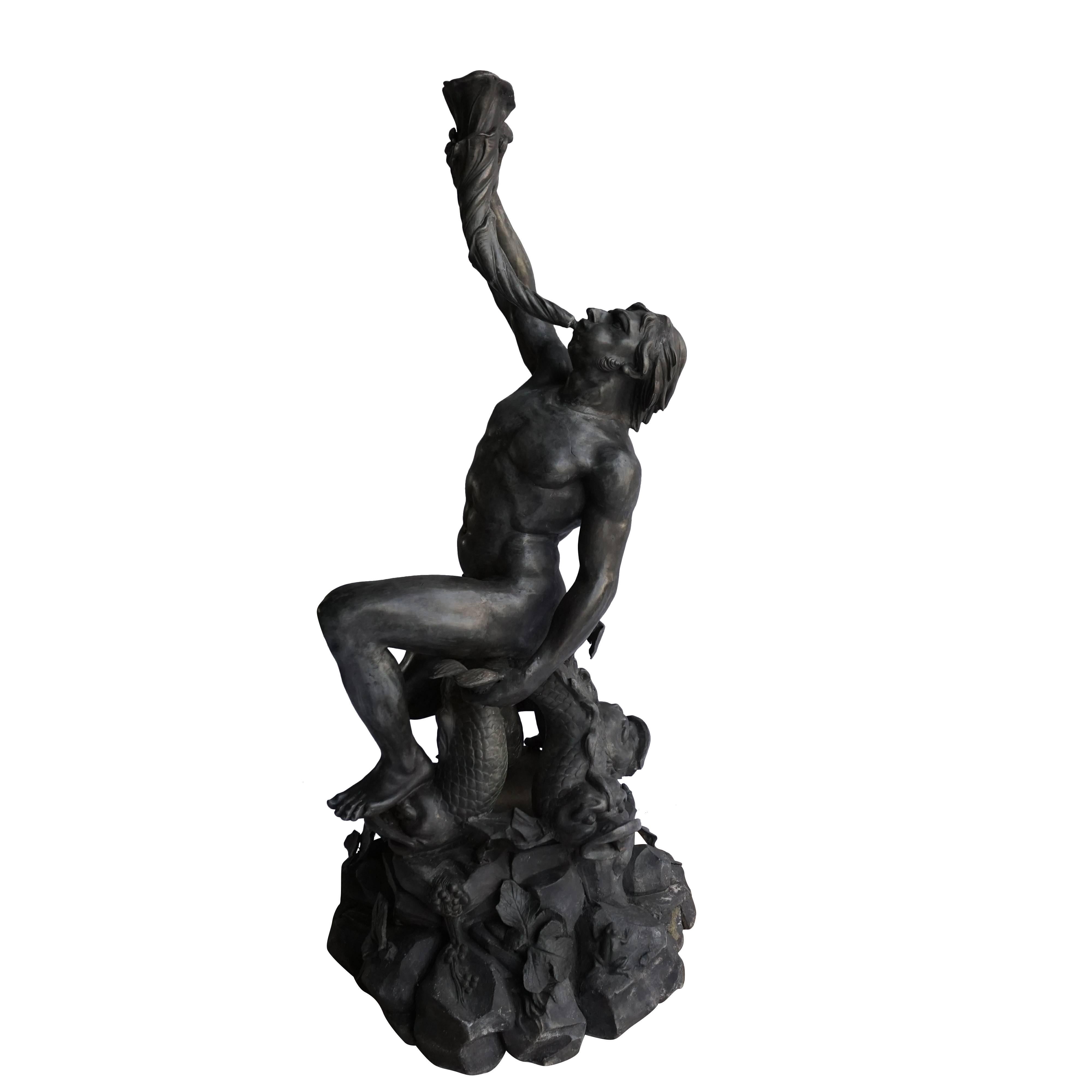 Metal triton sculpture holding a long decorative shell as a water feature and supported by three Dauphins grotesques, circa 1840-1850. The Grotto style base is decorated with small creatures for example with frogs, leaves and grapes. Very detailed
