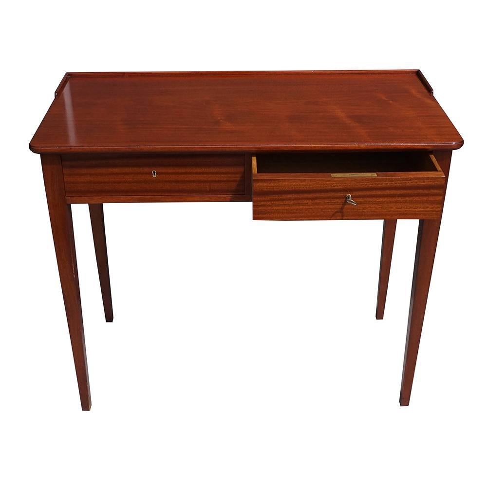 A Mid-Century writing desk with raised border in the back, finely tapered legs and two drawers, made of Teakwood. Wear consistent with age and use. Circa 1940, Denmark