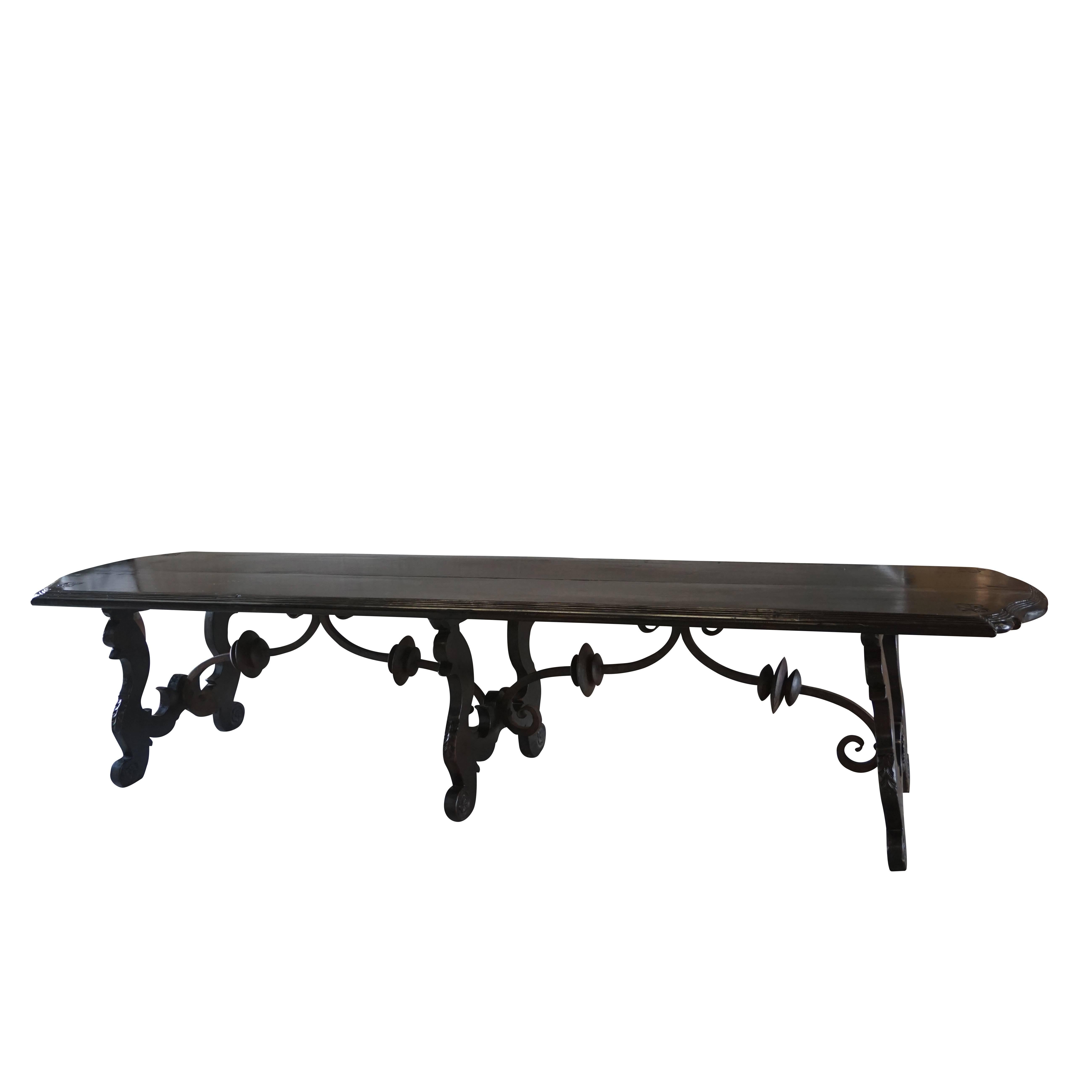 Exceptional large antique Tuscan refectory table in solid walnut with original scrolled hand-forged iron crossbars. The Lyra legs are hand-carved and supported by the beautifully worked hand-forged crossbars. The wooden tabletop is adorned with a