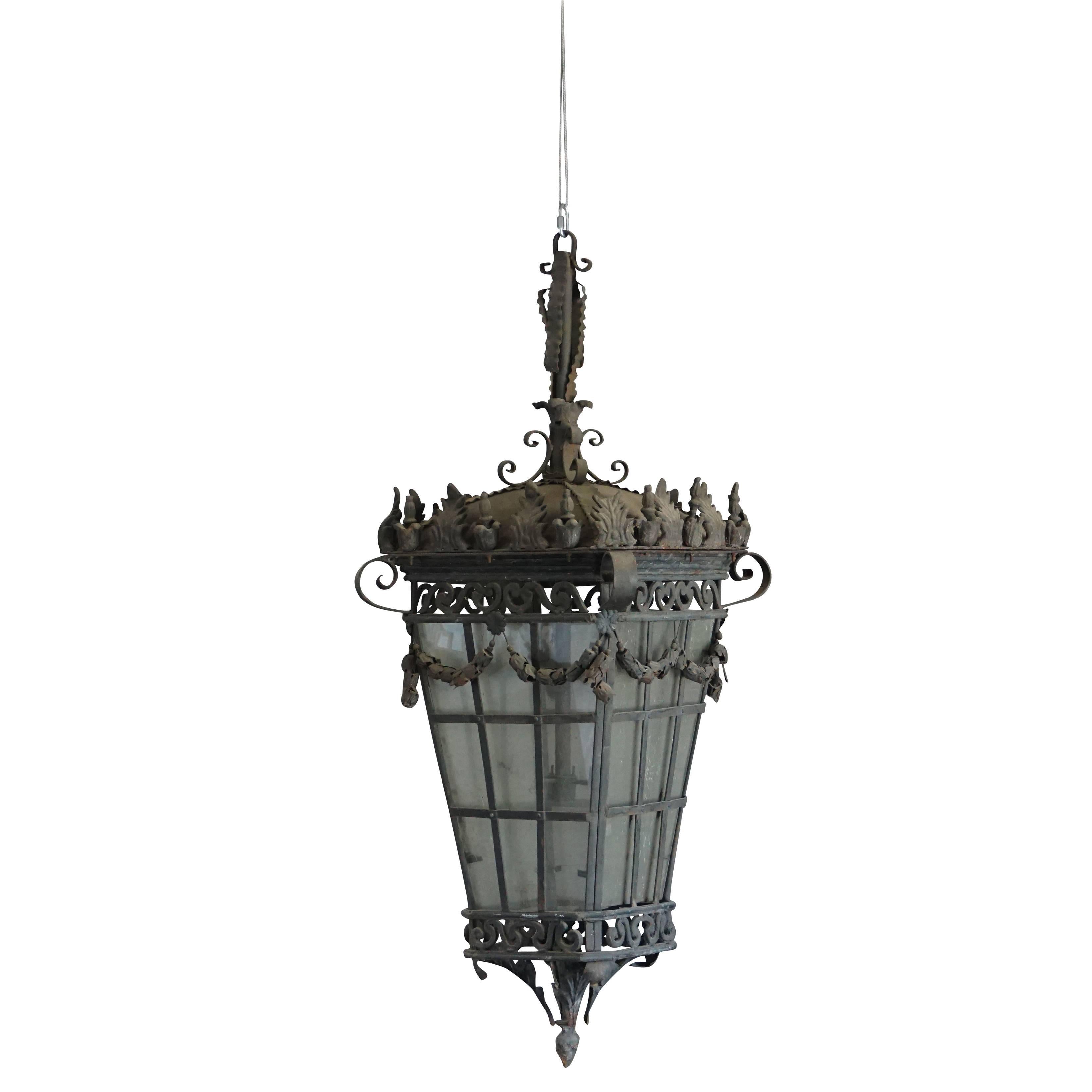 A large, vintage French Art Deco pair of monumental wrought iron hanging lanterns made of hand crafted metal and glass, enhanced by very detailed iron work, in good condition. Wear consistent with age and use. Circa 1920 Paris, France.
