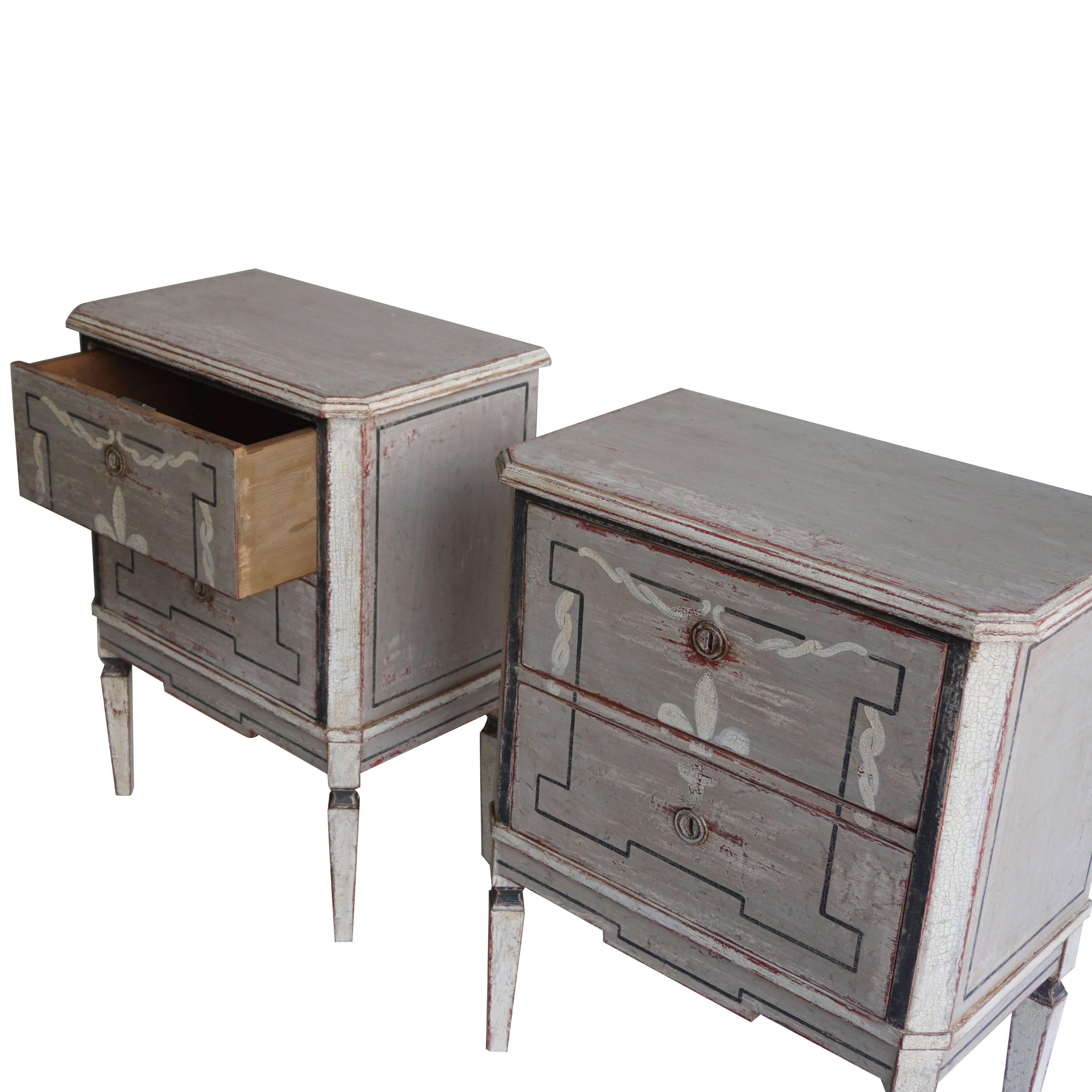 A pair of small handcrafted Swedish chests of drawers made of pinewood with a grey-white painted finish, fleur-de-lys decor on square tapered legs. The chests have two drawers with simple brass and hardware, circa 1880 Sweden, Scandinavia.
