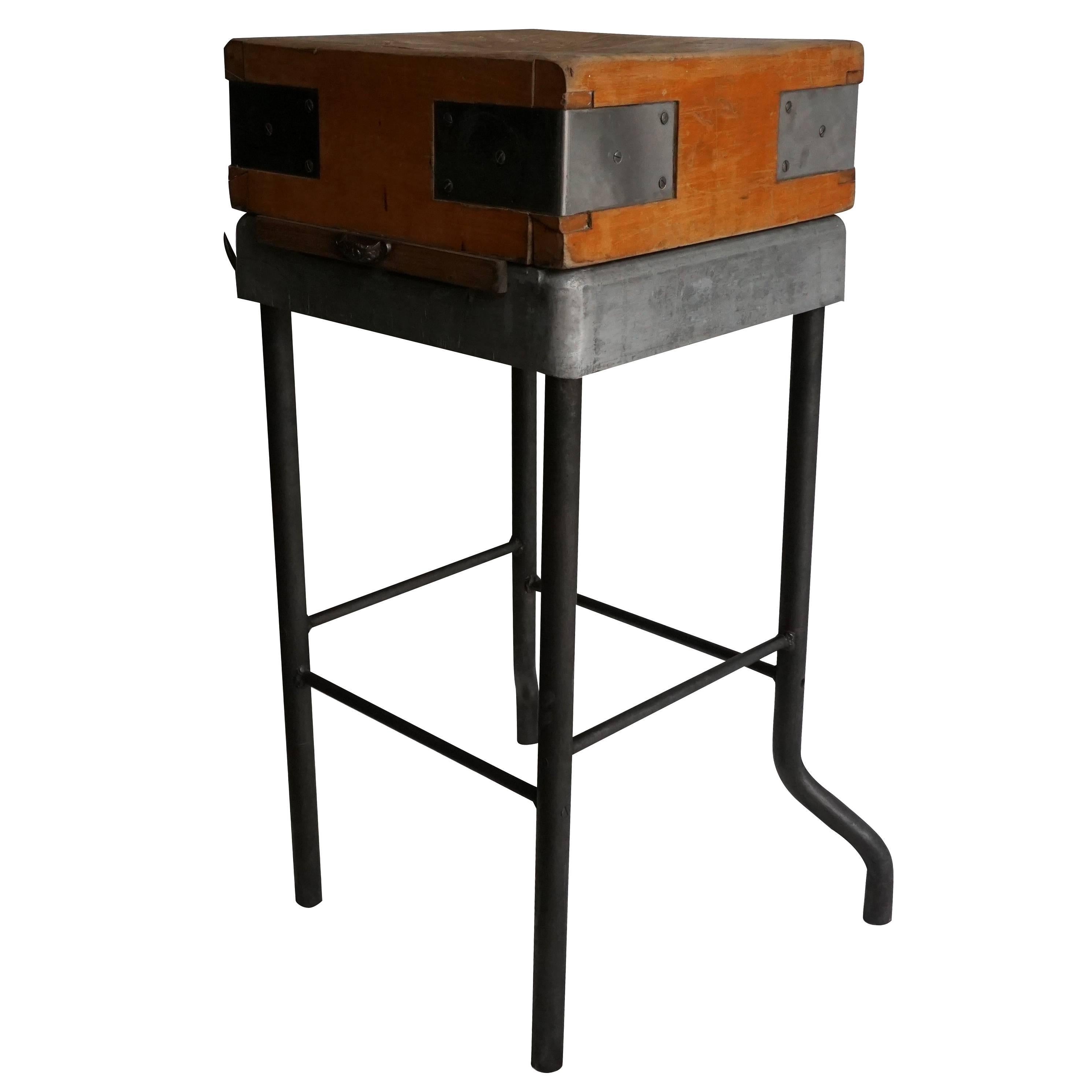 A rare vintage travelling butcher block from Strasbourg, France with a distressed, worn finish. The original butcher block is made of wood with reinforced metal corners. The block is was mounted on a steel base at a later date, with four lateral
