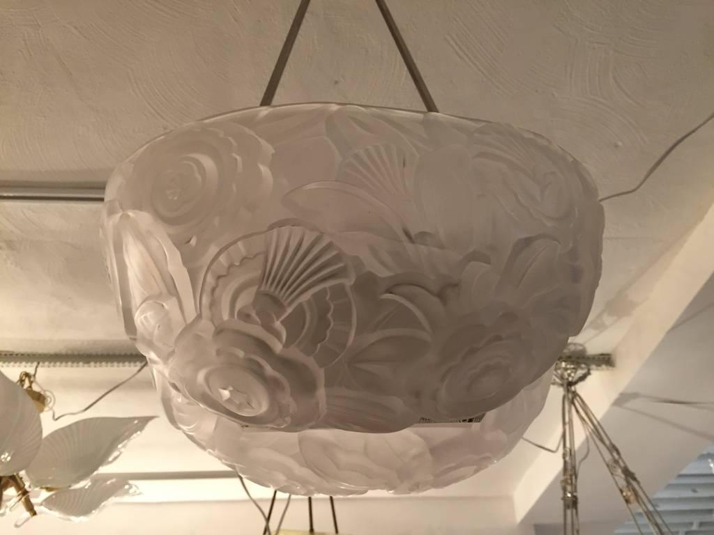 Lustre Art Déco français par l'artiste français Genet et Michon. Avec un abat-jour en verre moulé transparent et dépoli à deux faces. Les détails du motif des fleurs sont profonds. Soutenu par un cadre en nickel poli et une plaque de plafond
