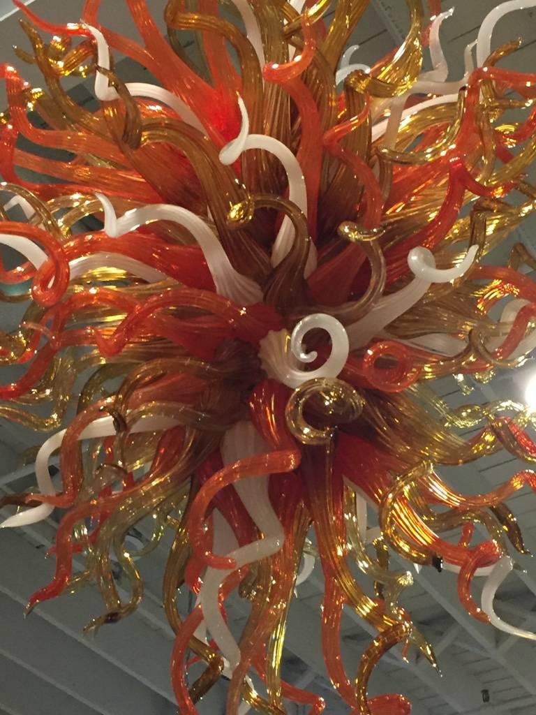 Handblown glass starburst chandelier. This incredible chandelier is made up of three different color glass, orange, gold, and white. The beauty of this chandelier is stunning and very captivating with the lights on or off. The time and craftsmanship