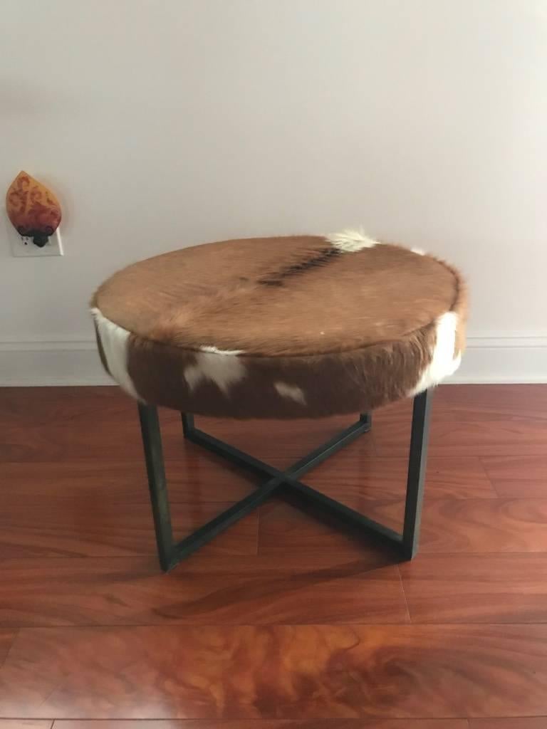 Round upholstered bench having cowhide supported on bronze washed metal base.
 