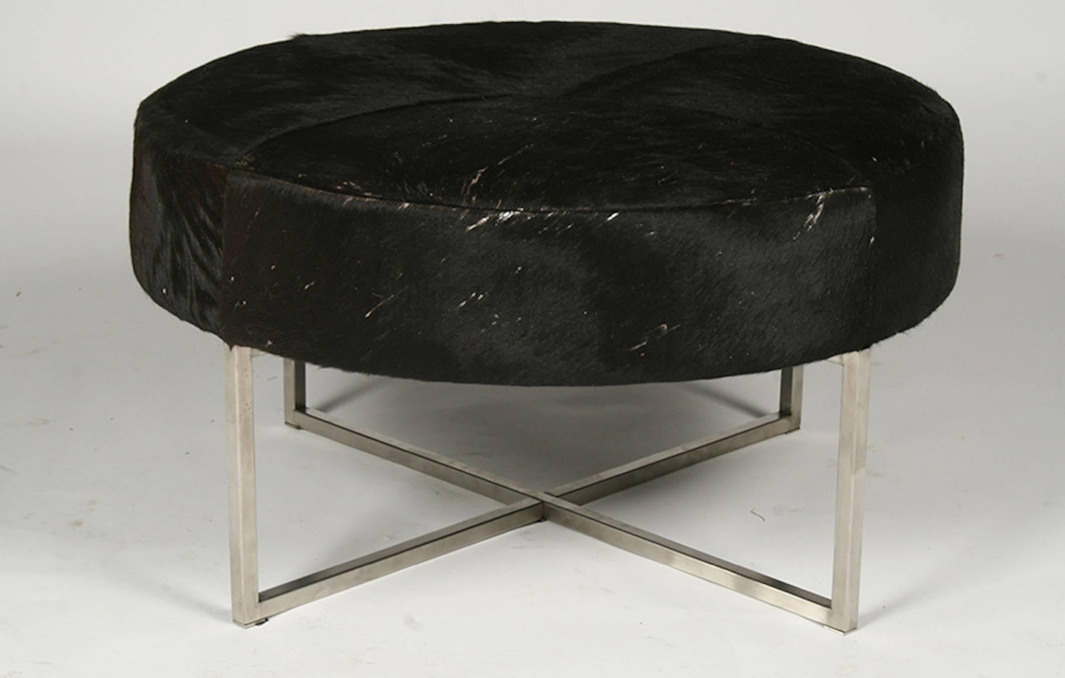 A Mid-Century Modern cow hide upholstered round bench or ottoman raised on a metal X-form base.