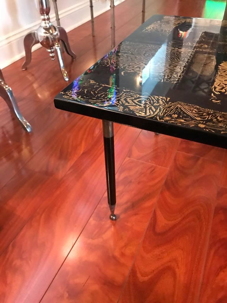 An Italian Mid Century Modern Laqured coffee table having gold gilt foil and ebonize lacquer decorated top supported on metal legs, circa 1960.