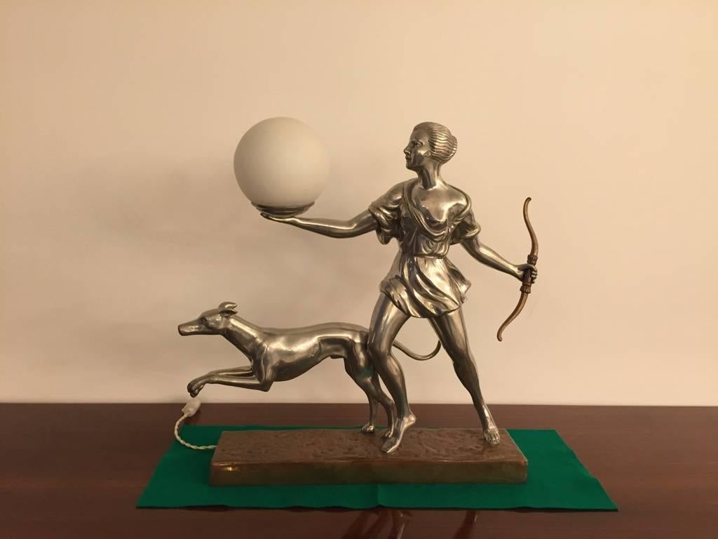 Beautiful French Art Deco table lamp of hunter and dog in nickel with copper base. Stunning details from the bow all the way to the dog. Globe lights up. 

2/300 signed by vincent 