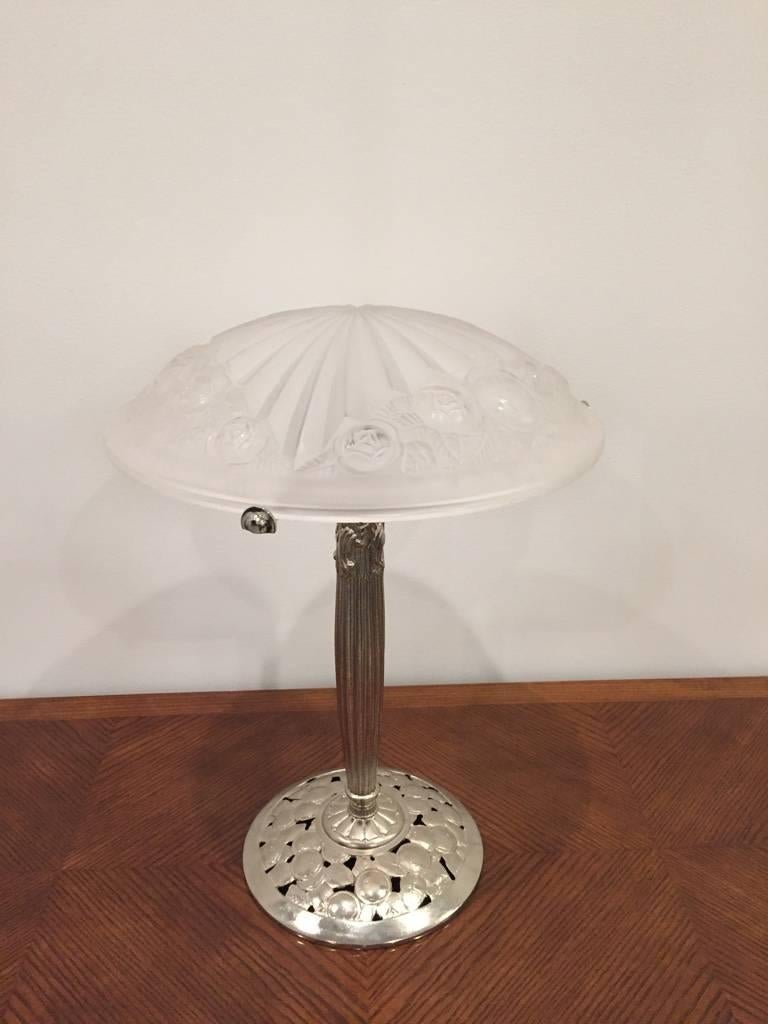 A stunning French Art Deco table lamp created in the 1930s signed by Degue. Having clear and frosted glass shade with geometric and floral motif. Shade is held by a polished nickel floral base.