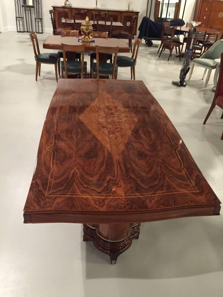 This amazing French Art Deco dining table is in the style of Jules Leleu. Can be extended with two leaves on either side of the table. Rosewood and silver trim along with mother-of-pearl inlay accompanying a center flower motif. The legs are breath