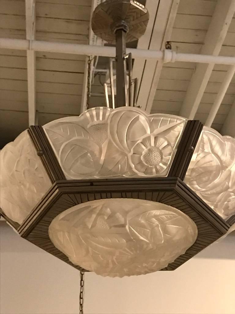 Stunning French Art Deco chandelier signed by Degue with six outer panels and a large center bowl. The glass has a flower motif and is all signed Degue. Supported by matching layered multi-tiered, geometric design silver bronze frame.

Re-plating