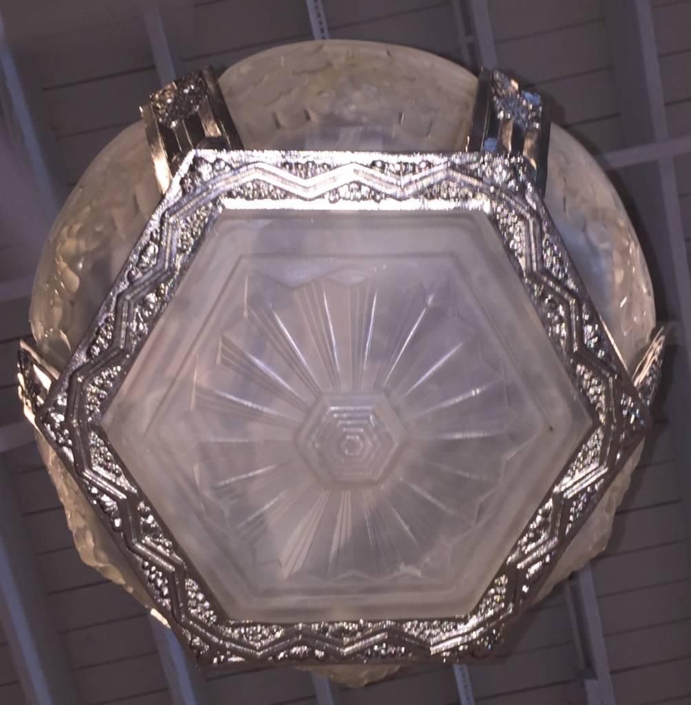 Stunning French Art Deco chandelier. Having six outer panels in molded clear frosted glass decorated with geometric and fruit motif. The center panel having geometric motif details. Supported by matching geometric and fruit motif design silver
