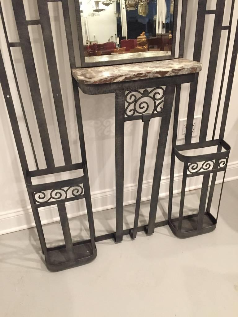 Beautiful French art deco wrought iron and marble hall tree. Having four coat hangers with two umbrella stands, center mirror and hat rack. The deco detail is gorgeous and quite stunning.