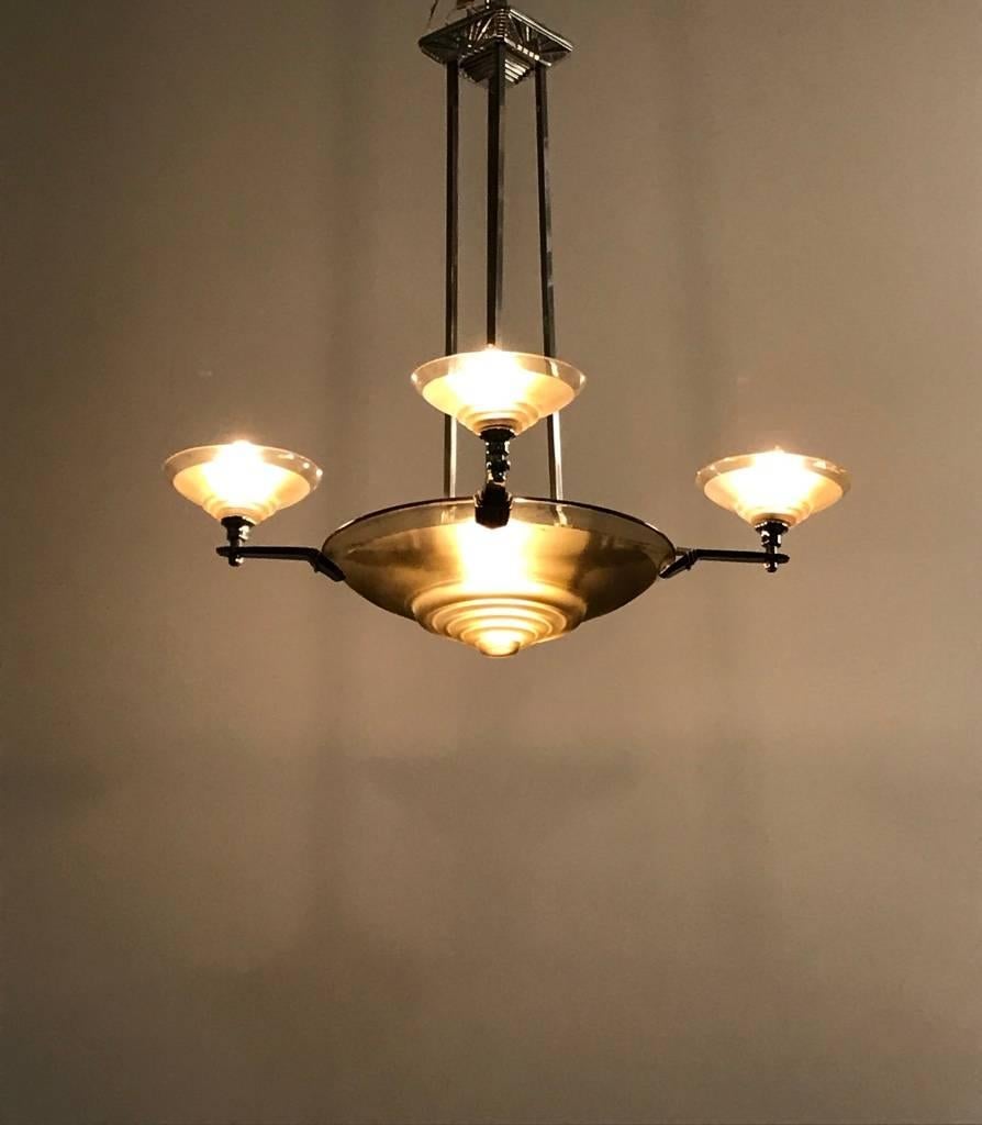 This French Art Deco chandelier was made in the 1930s by the firm Muller Freres, located in Luneville. The chandelier has a central bowl and four smaller bowls of smoked glass, all partially etched. Each bowl has four graduated rings before