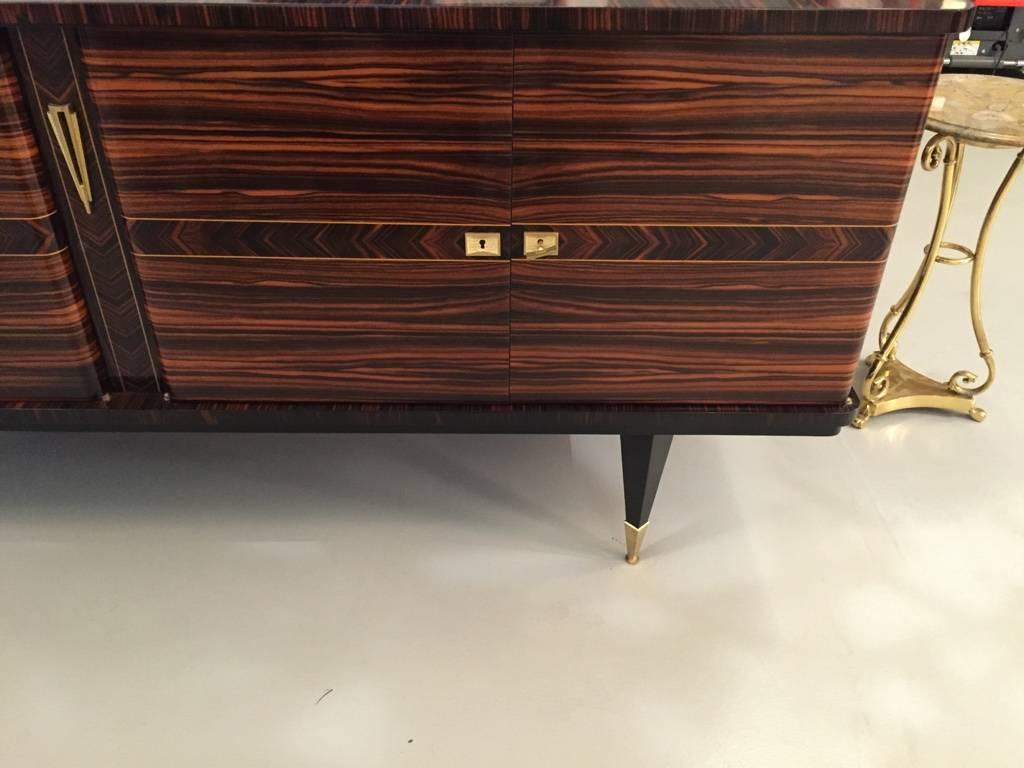 This stunning French Art Deco exotic Macassar ebony buffet or credenza, circa 1940s. Has a dry bar and plenty of storage. Interior finished in lemonwood and black lacquered legs.