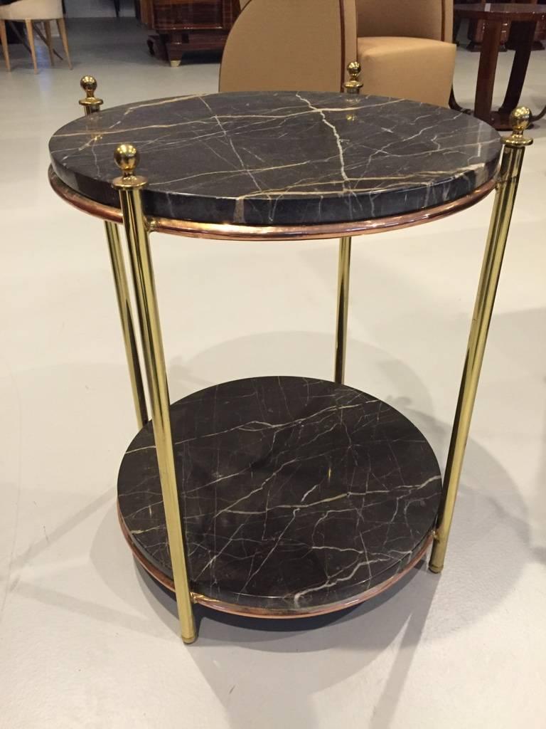 This French Art Deco occasional table was designed by Jacques Adnet, circa 1940 and is of brass and copper with two marble surfaces of black and brown marble with white inclusions. The brass and copper have been polished and coated with clear