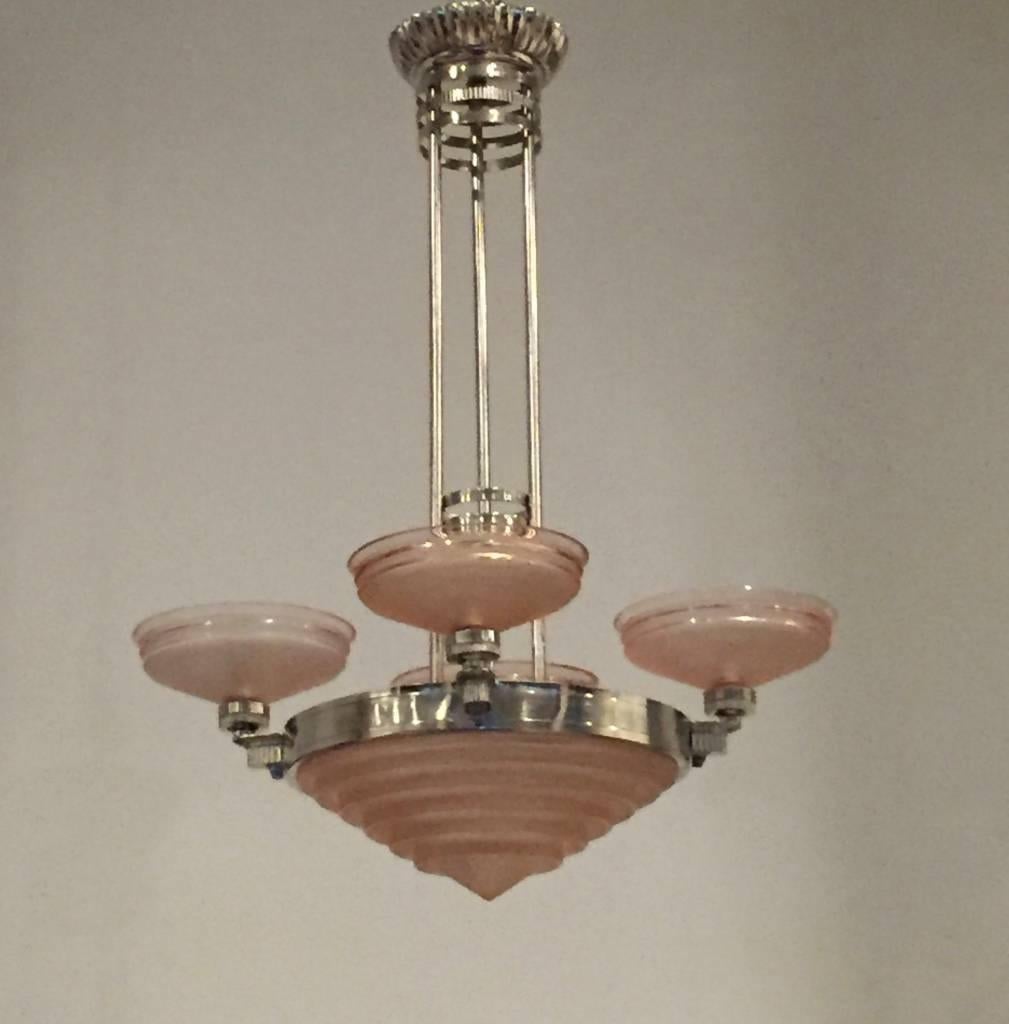 Stunning French Art Deco chandelier signed by G. Leleu. With beautiful pink frosted molded glass shades with geometric motif. Having polished details mounted on a silvered bronze frame with a geometric design. Giving off beautiful amount of light.